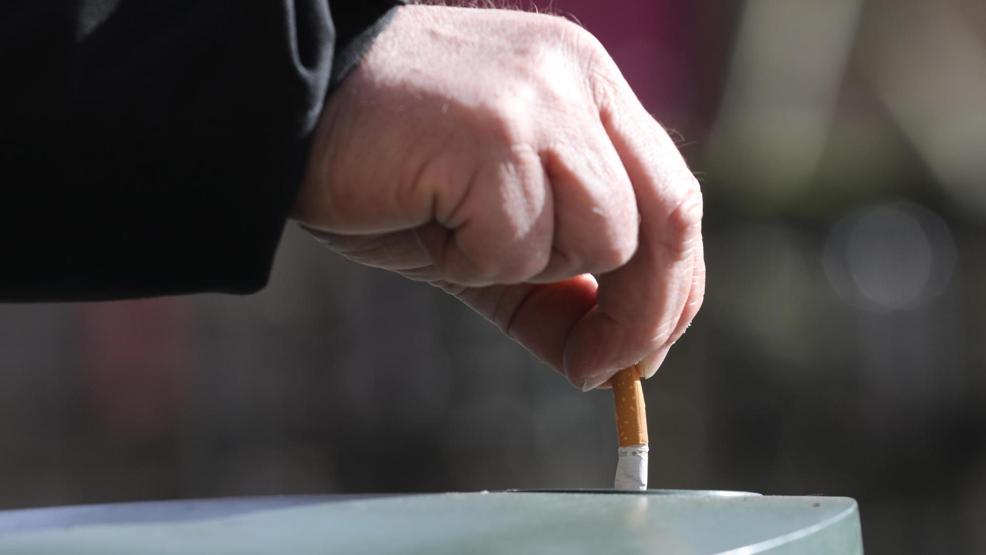 Una persona apaga un cigarrillo.