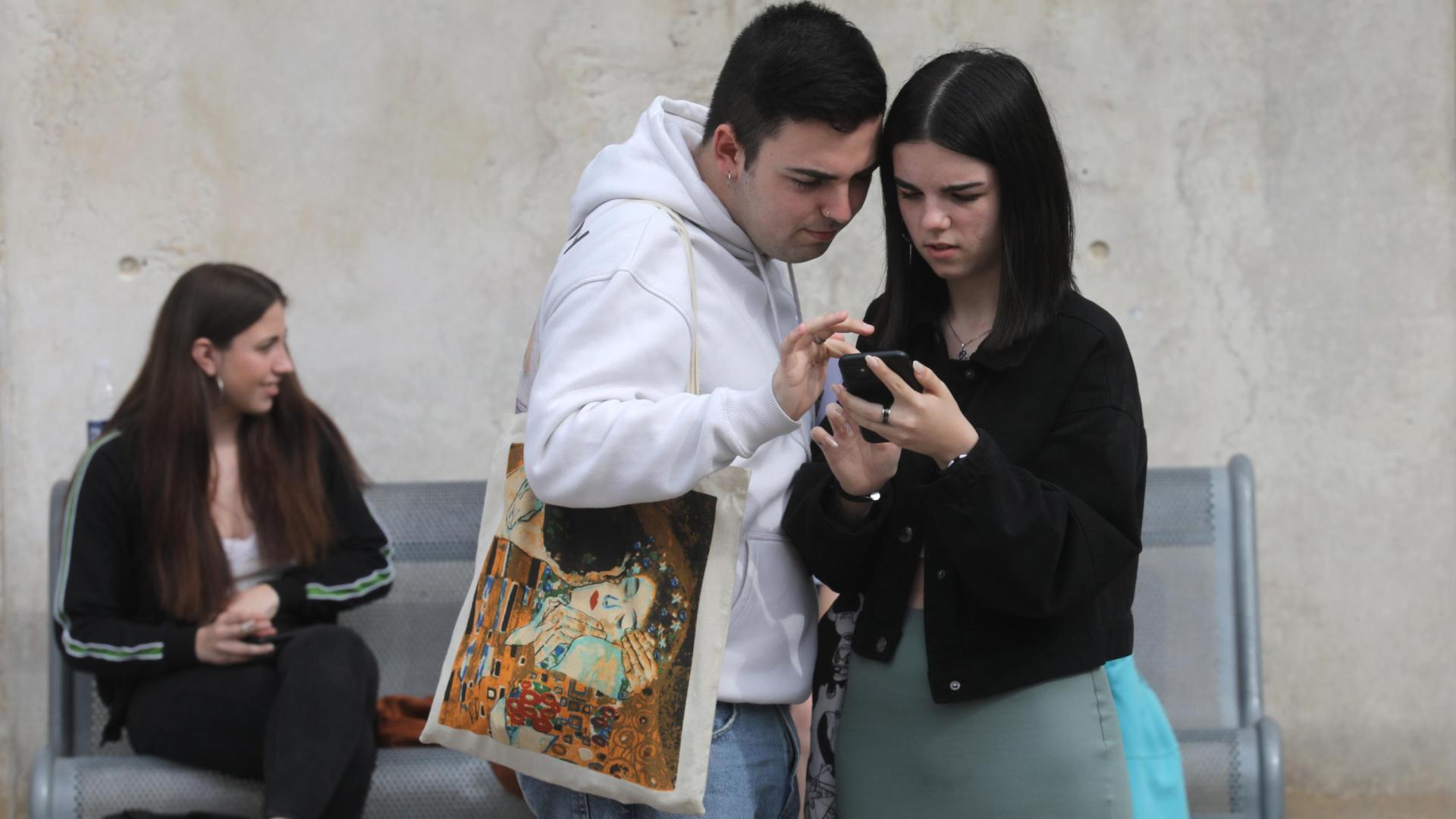 Dos alumnos que han realizado la EvAU consultan el móvil en la UPNA