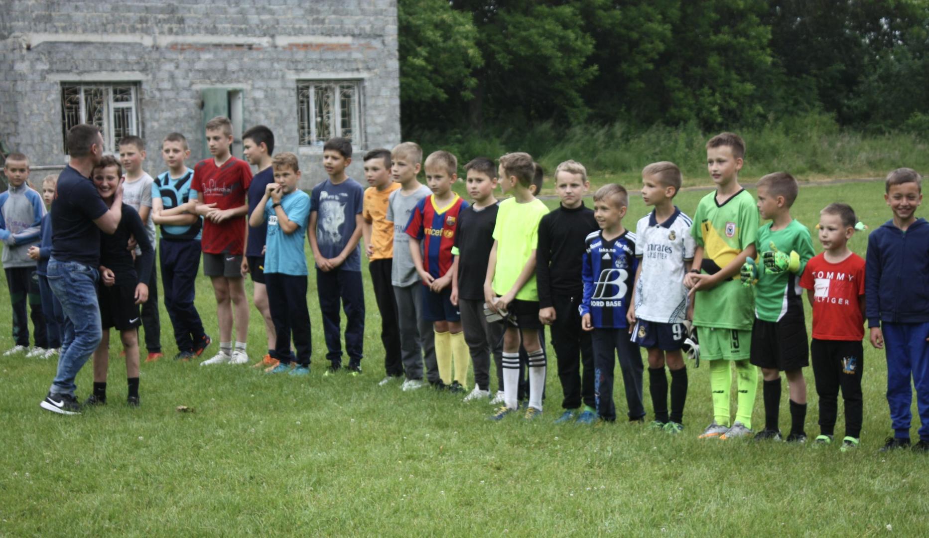 Varios niños de la zona de Kernytsya esperan en fila para recibir sus nuevas camisetas.