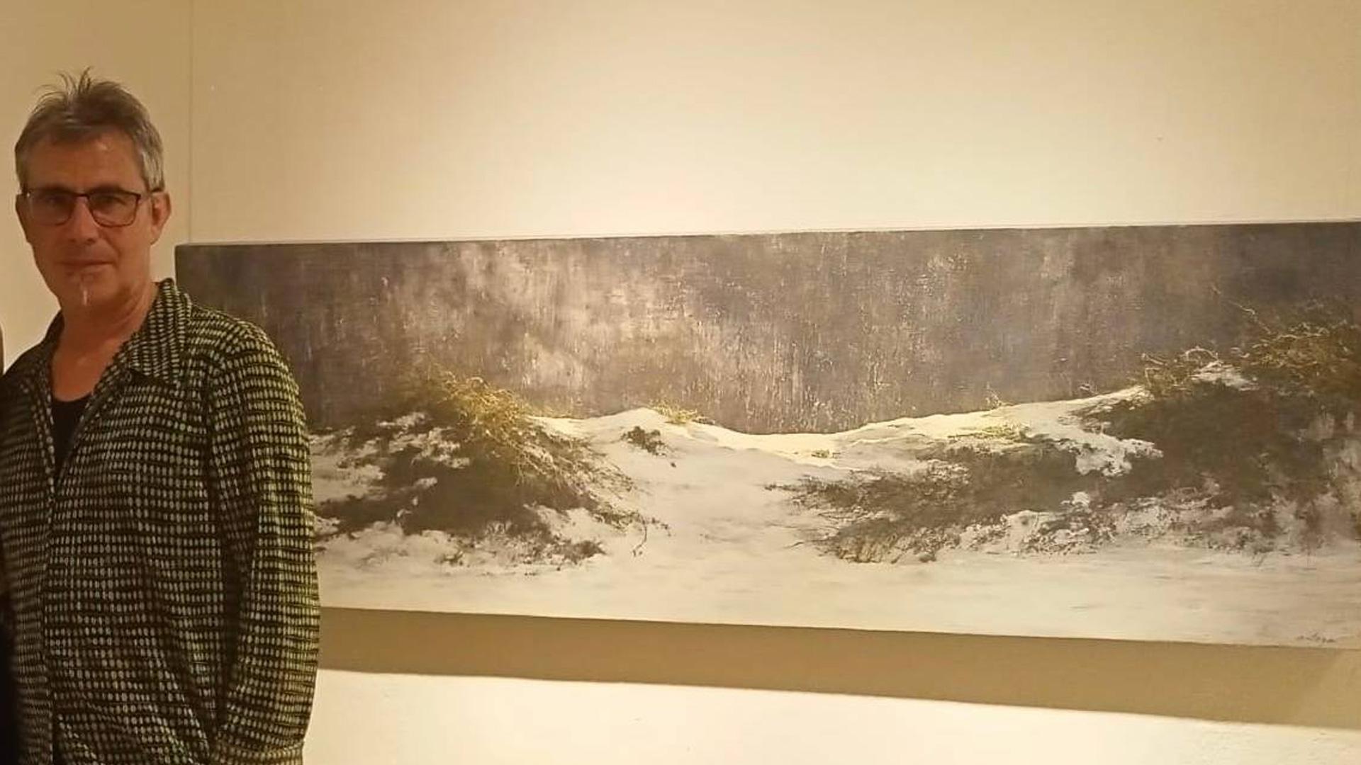 El artista riojano Juan José Ortega, junto a uno de los paisajes nevados que forman parte de la exposición que presenta en Pamplona