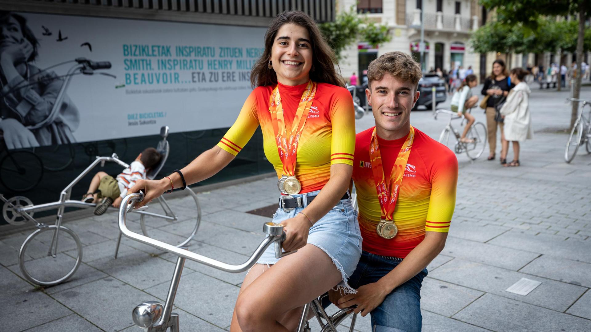 Los ciclistas Idoia Eraso y Unai Aznar, campeones de España, posan con sus maillot y sus medallas en el conjunto escultórico ‘Diez bicicletas’