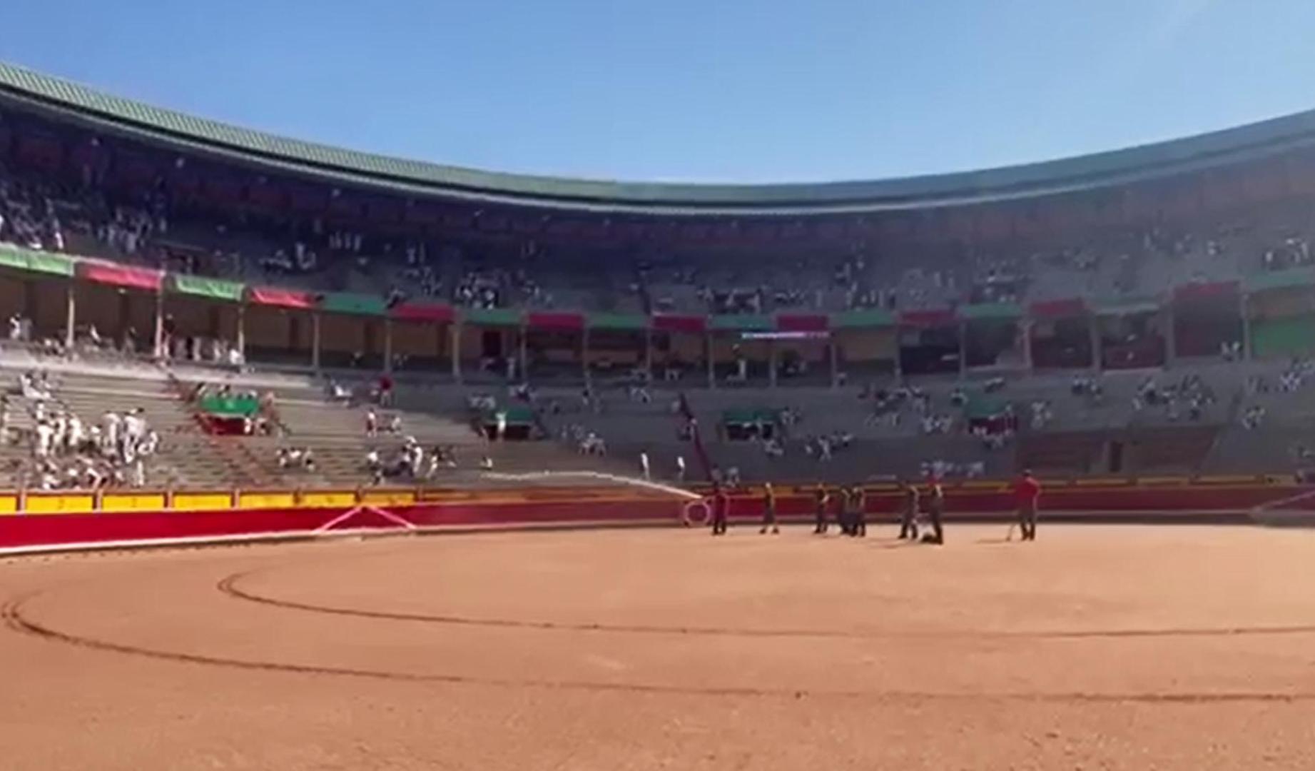 Los areneros riegan la arena de la plaza de toros antes de la corrida del 9 de julio