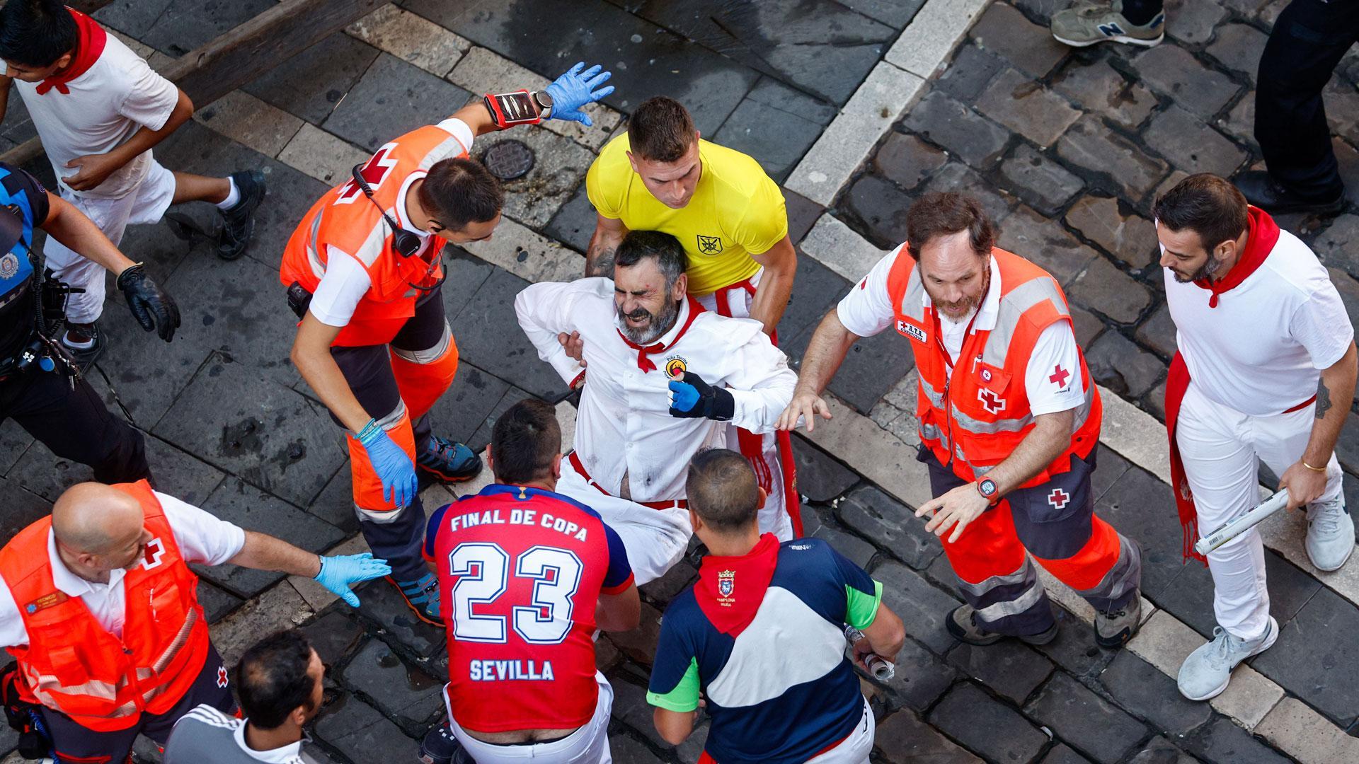Mozos y sanitarios trasladan a un herido durante, durante el octavo y último encierro de sanfermines este viernes en Pamplona con los legendarios toros de la ganadería de Miura
