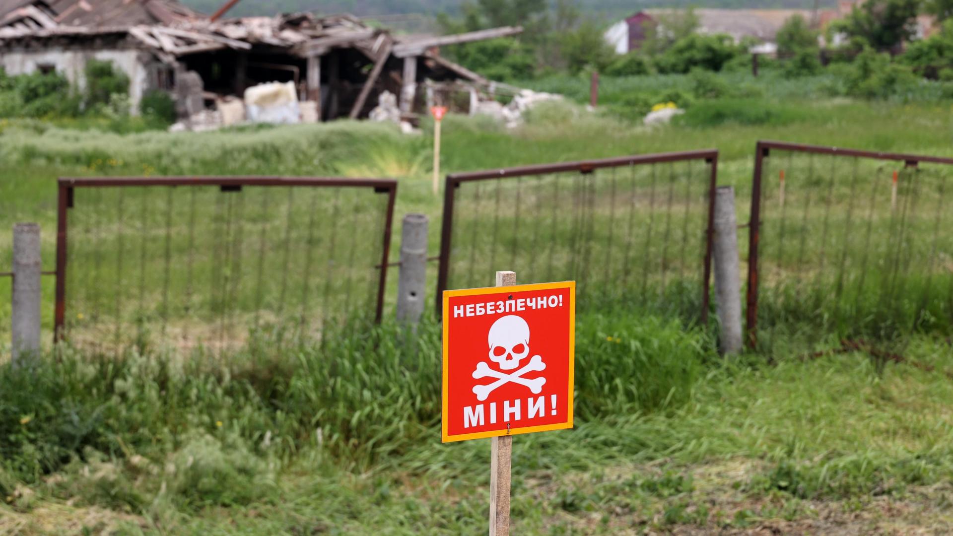 Una señal de ''¡Precaución! Minas'' en la zona de pruebas de una máquina de desminado humanitario construida sobre la base de un tractor T-150 por ingenieros de Kharkiv, región de Kharkiv, noreste de Ucrania.