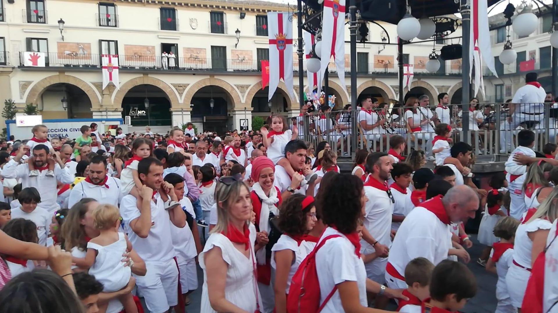 Niños y niñas acompañados de sus padres, madres u otros familiares giran en torno al kiosco de la plaza de los Fueros al son de la música manteniendo la tradición