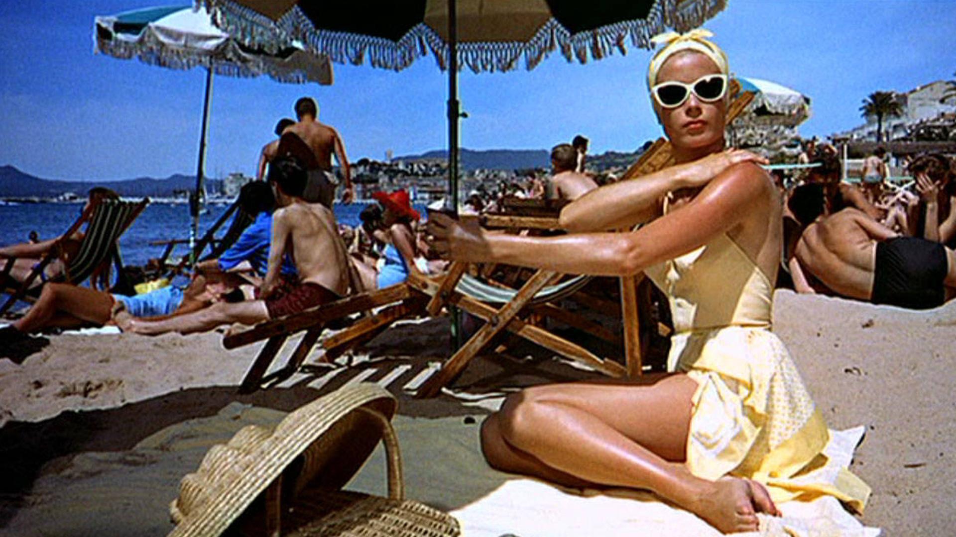 ‘GLAMOUR’ QUE RESPIRA VERANO  Me maravilla el estilo de Grace Kelly aplicándose crema solar bajo el sol abrasador del Mediterráneo en la Riviera francesa. ‘Glamour’ personificado el que destila en ‘Atrapa a un ladrón’, dirigida por Alfred Hitchcock en 1955, y en la que interpreta a una rica heredera que disfruta de sus vacaciones de verano con su madre. Entre baños de sol y sal, se cruza en su vida un seductor Cary Grant, en este caso ladrón de joyas ya retirado de su ‘oficio’ que debe demostrar su inocencia. La acción transcurre en lujosos hoteles, casinos y paisajes espectaculares y entre los dos protagonistas, claro está, saltan chispas. Una película que, aunque es considerada de tono menor, más romántica que de intriga, dio un giro copernicano a la vida de la estrella del celuloide, una de las actrices favoritas del mago del suspense.  Durante el rodaje, Grace Kelly conoció al príncipe Rainiero de Mónaco que, un año después, se convertiría en su marido. El resto ya es historia.