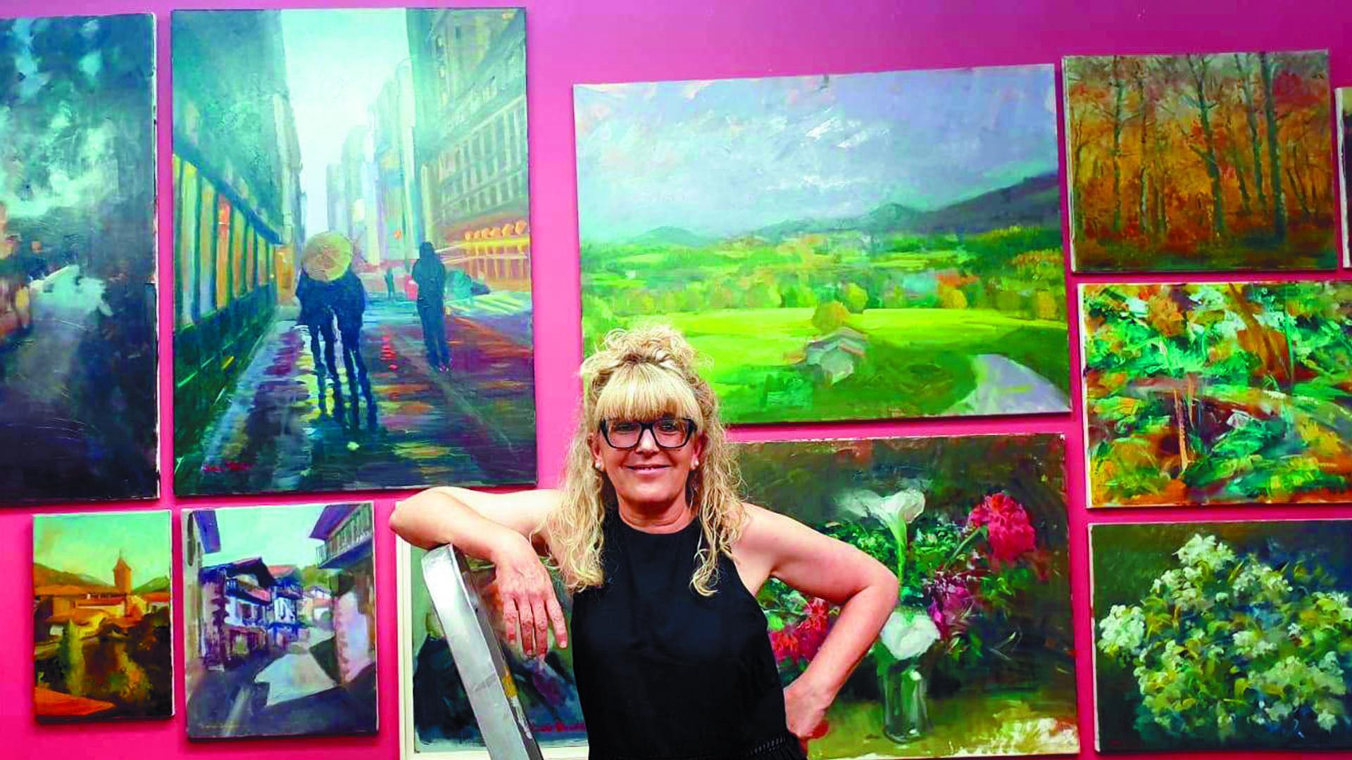 Diana Iniesta junto algunas obras de  la exposición Allegro vivace en la que comparten protagonismo los paisajes, las composiciones florales y la figura humana