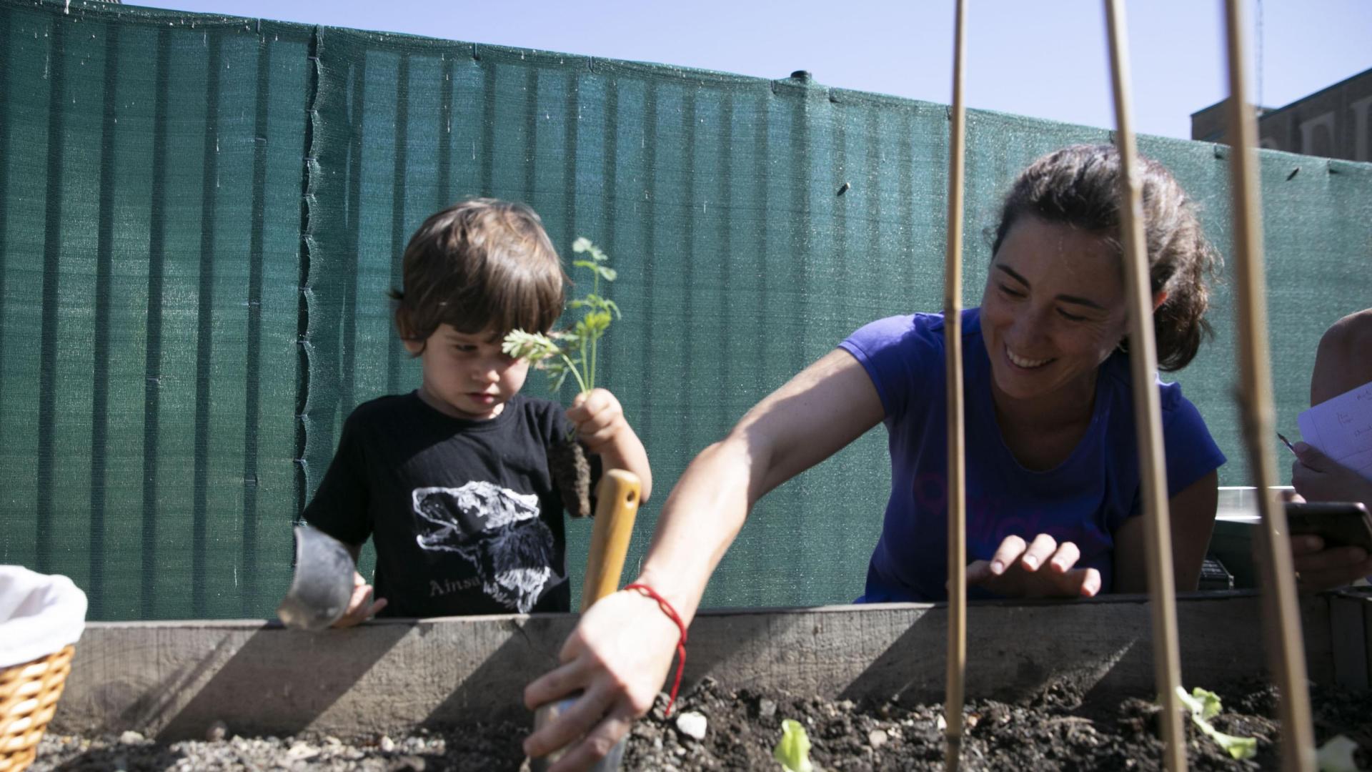 Nahia Izuriaga, educadora, planta lechugas junto a Elur, uno de los niños que ayer empezaron curso en la escuela infantil de Mendillorri