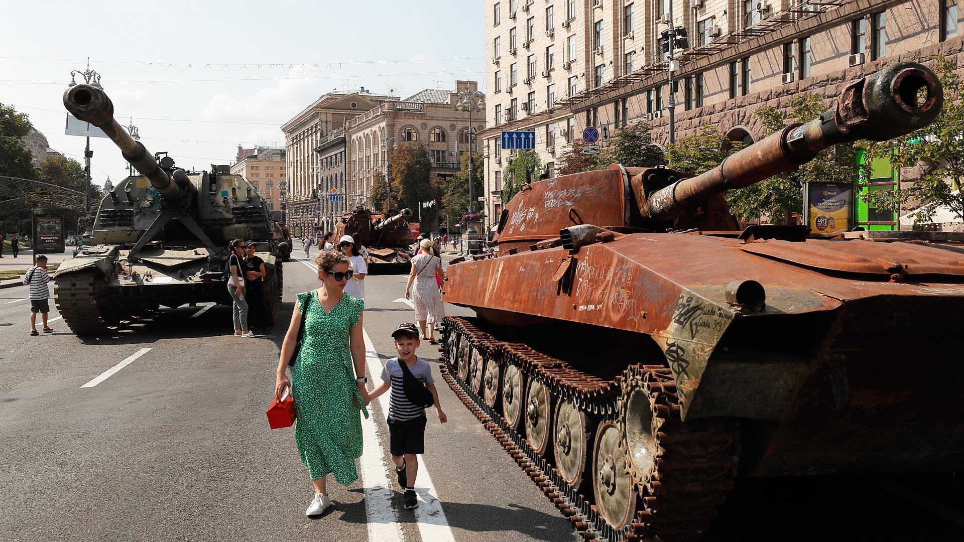 Varias personas caminan entre vehículos militares rusos dañados y tomados por el ejército ucraniano en Kiev