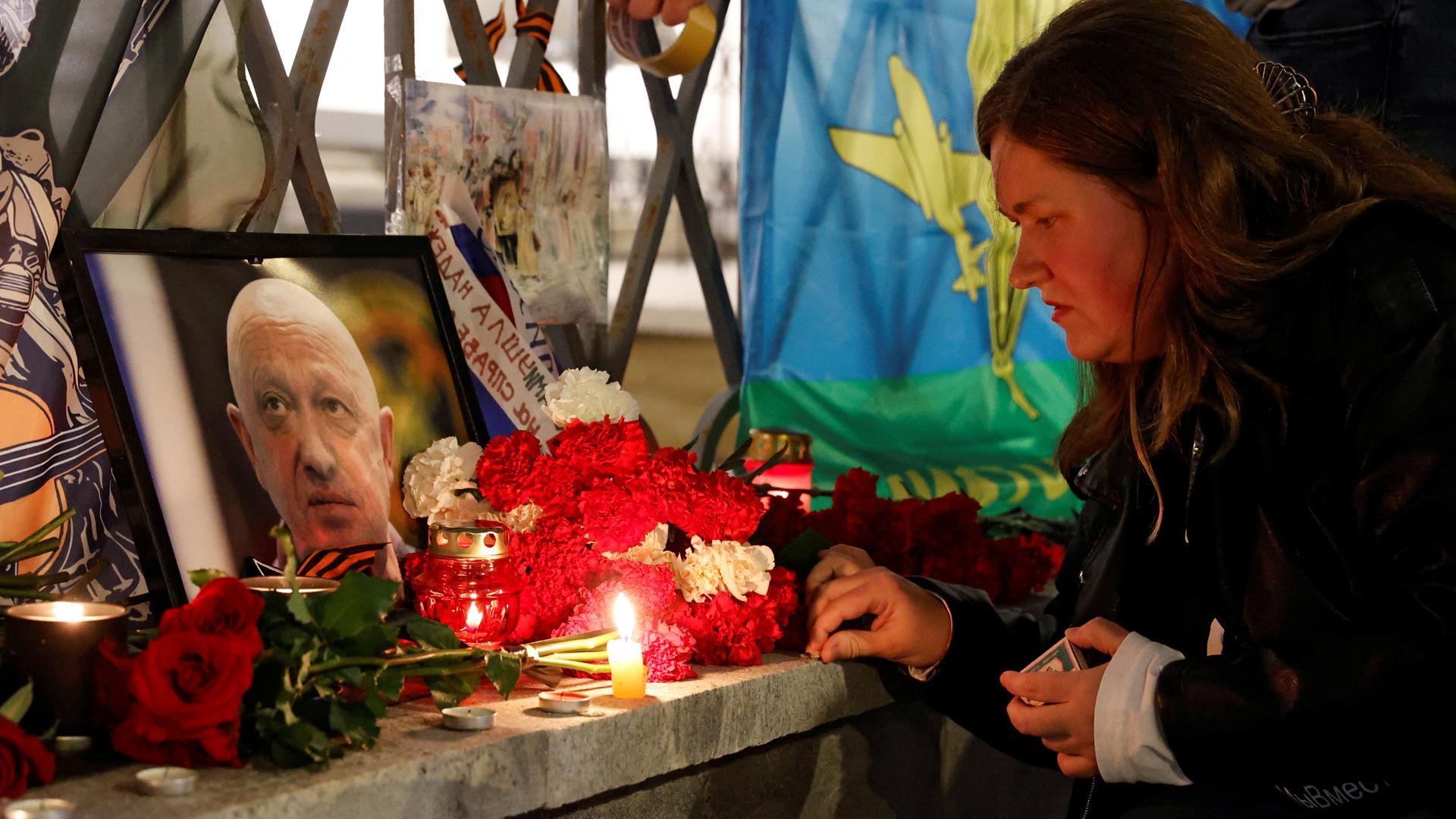 Una mujer enciende una vela frente a un retrato del jefe de los mercenarios de Wagner, Yevgeny Prigozhin, en un monumento improvisado en Moscú, Rusia