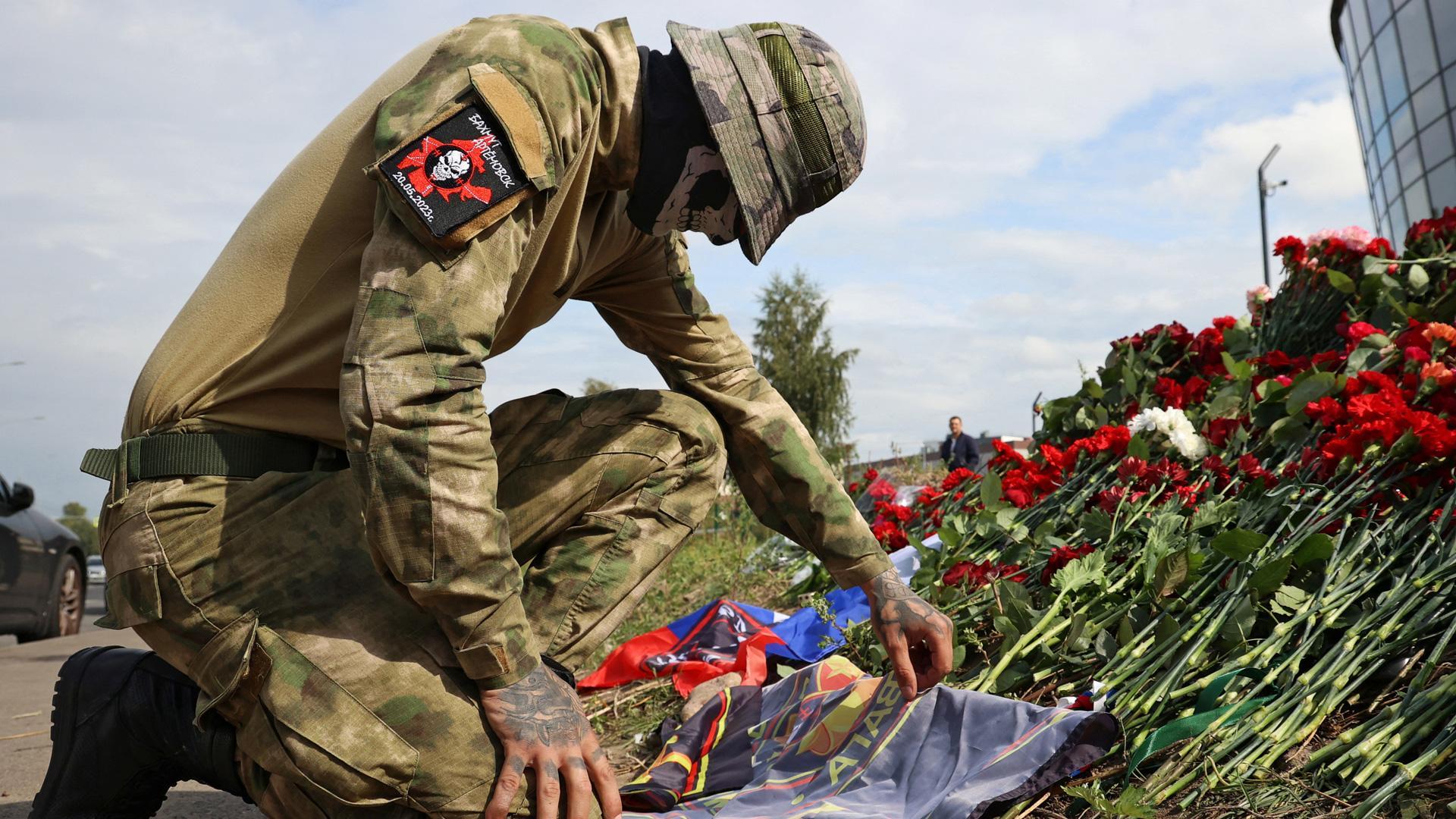 Un mercenario deja flores frente a las oficinas de Wagner en San Petersburgo en recuerdo de Prigozhin