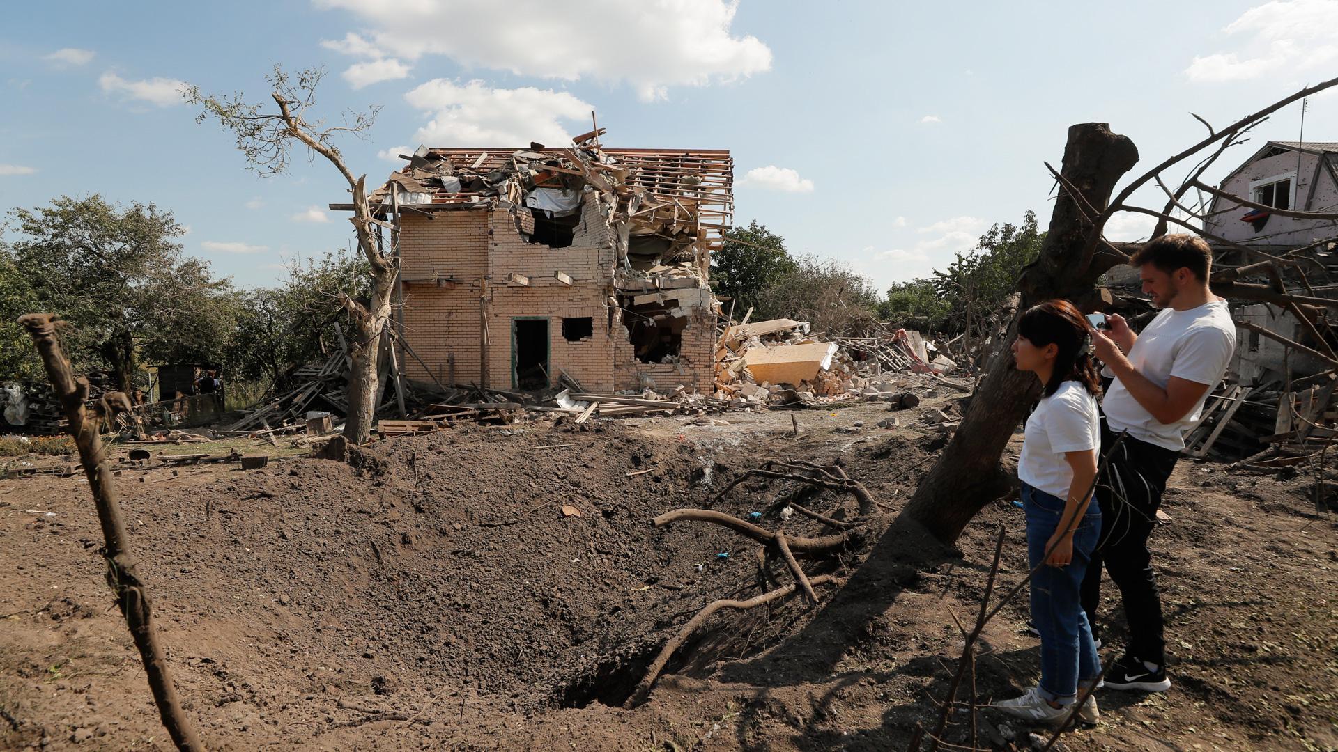 Una pareja mira los daños causados por un cohete ruso cerca Kiev, en Ucrania