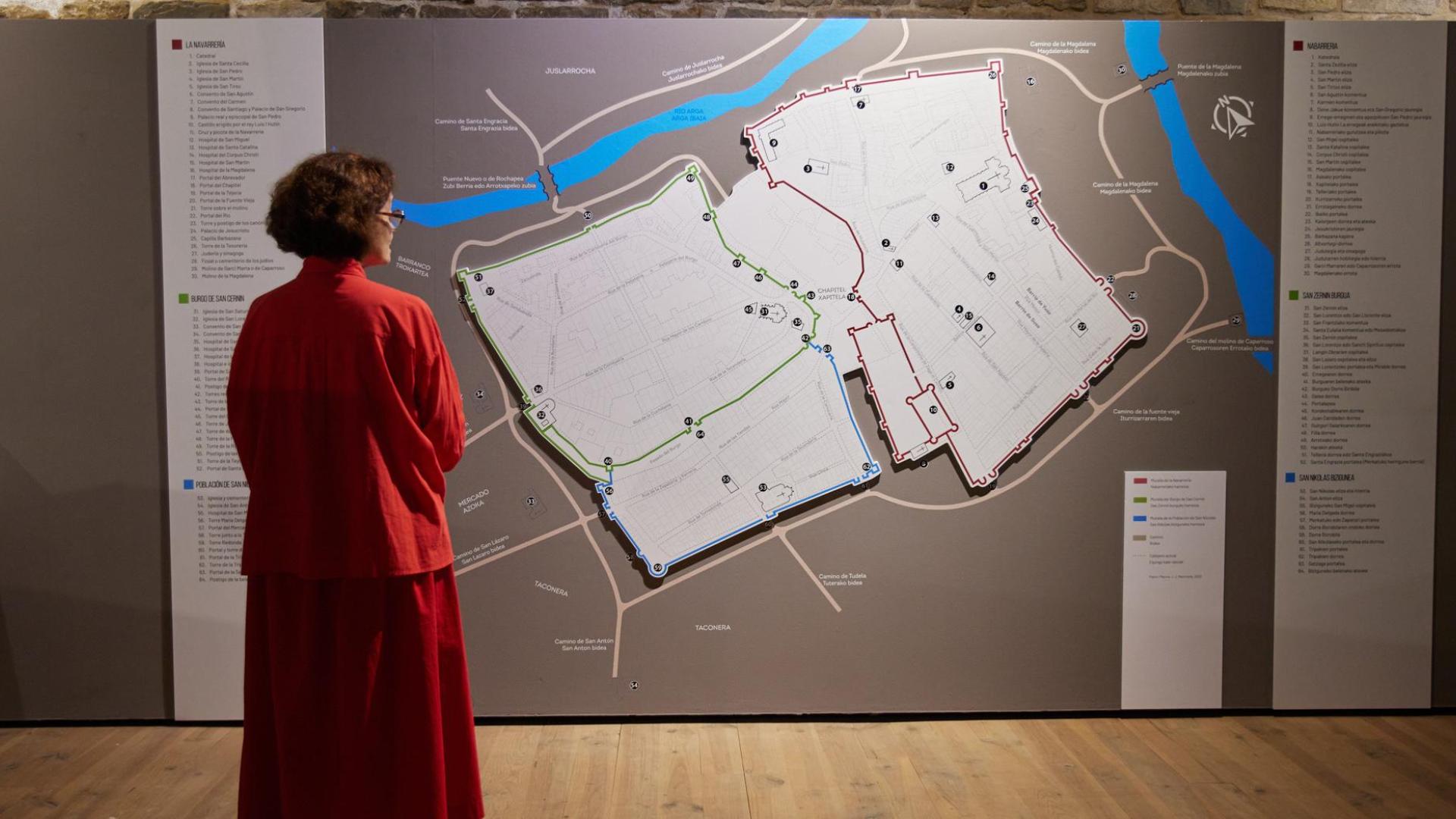 La directora del Museo de Navarra, Mercedes Jover, invitada a la inauguración, contempla el mapa de los tres burgos de Pamplona que puede verse en la exposición