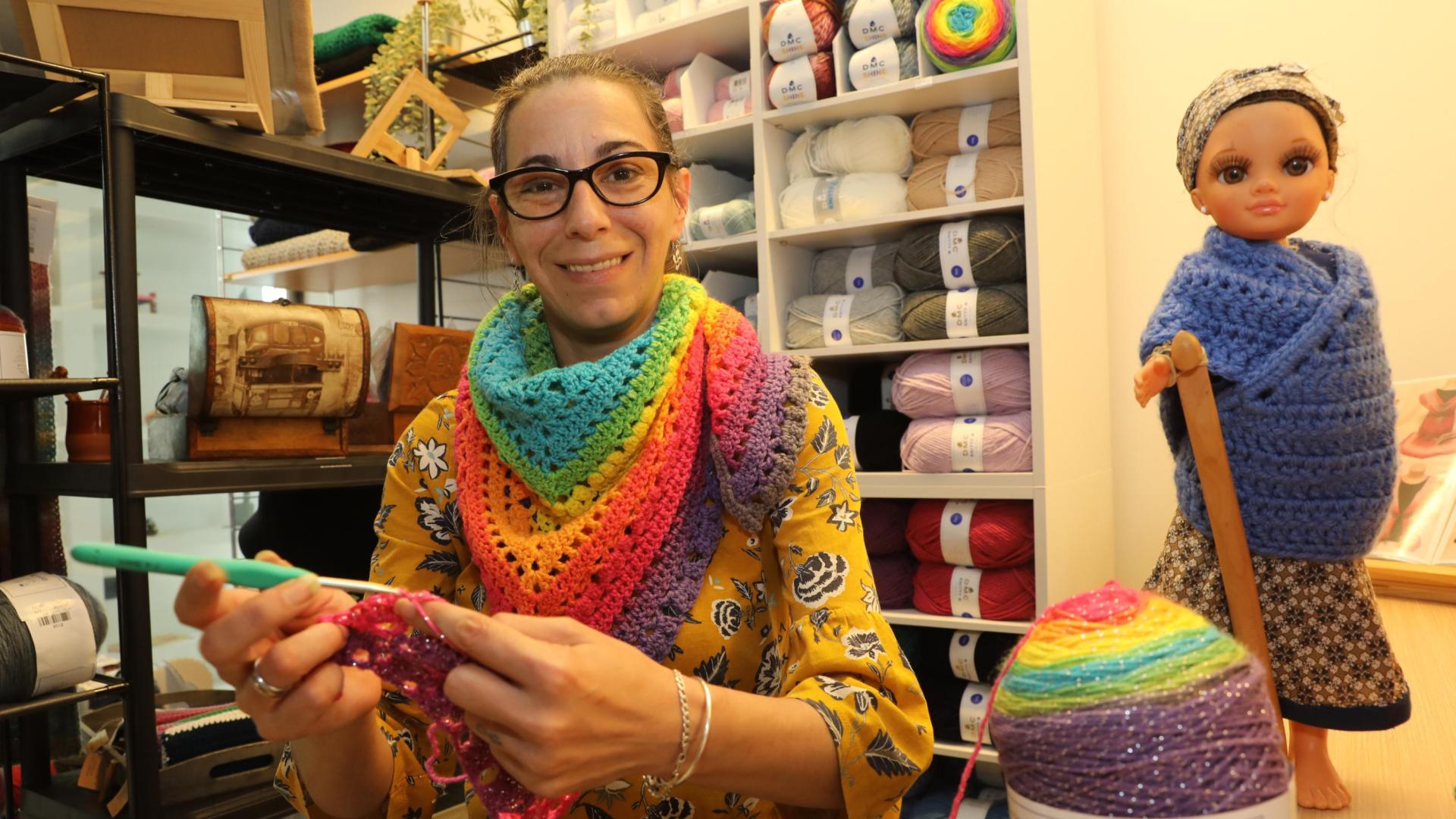 Lluna Barquero tejiendo una bufanda de colores en su nueva tienda.