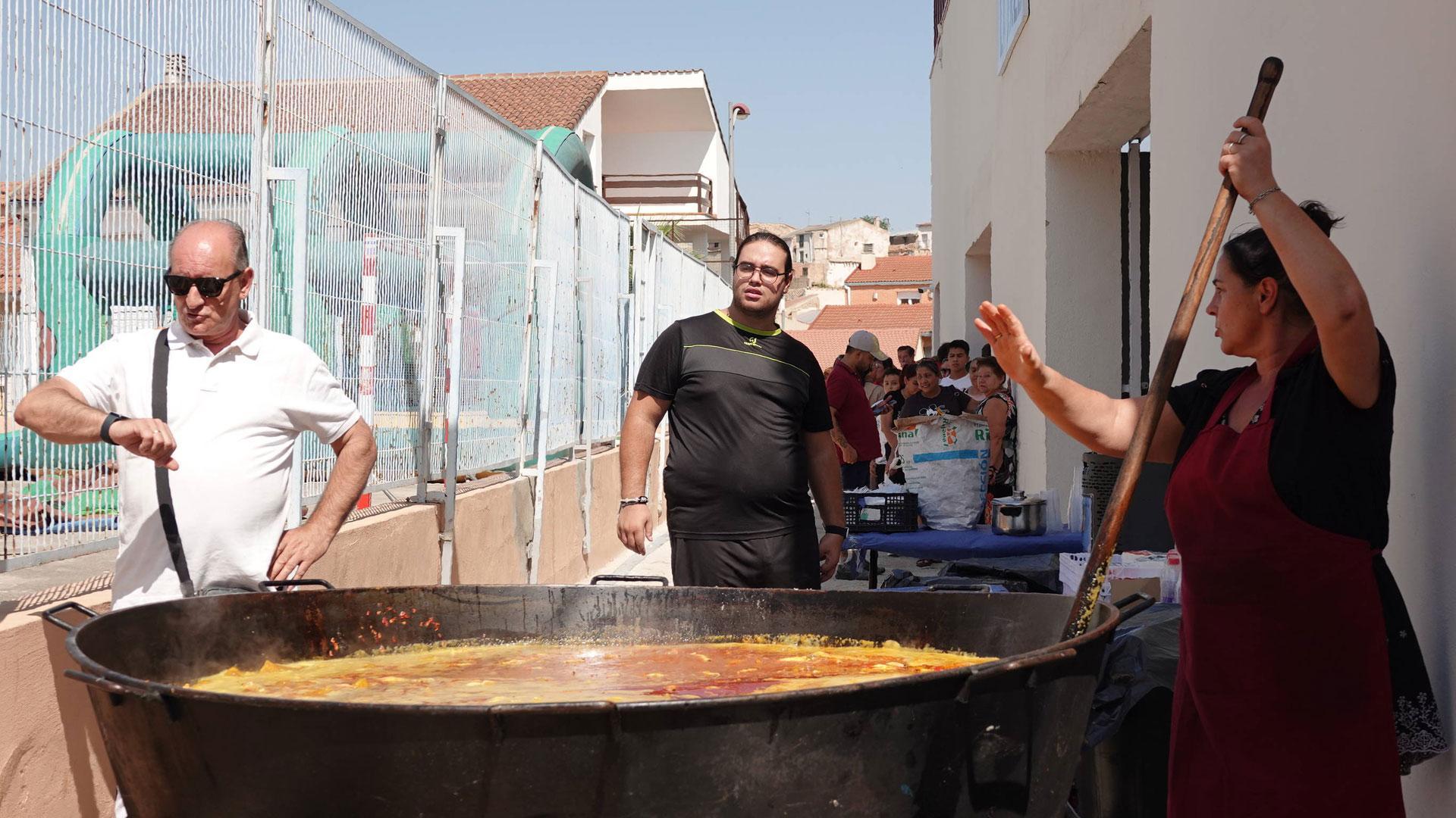 El concejal Joaquín Bermejo mira al reloj, mientras la cocinera se afana con la paella