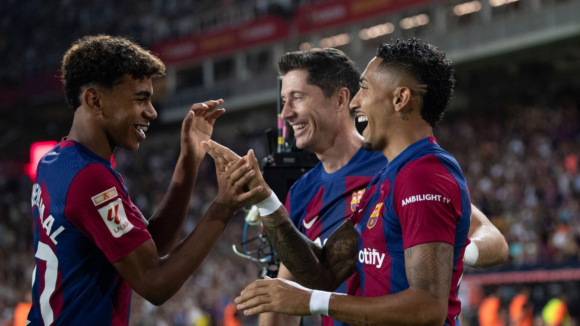 El delantero brasileño del FC Barcelona, Raphinha (d), celebra el cuarto gol del equipo blaugrana durante el encuentro correspondiente a la quinta jornada de primera división que disputan hoy sábado frente al Betis en el estadio Olímpico de Montjuic