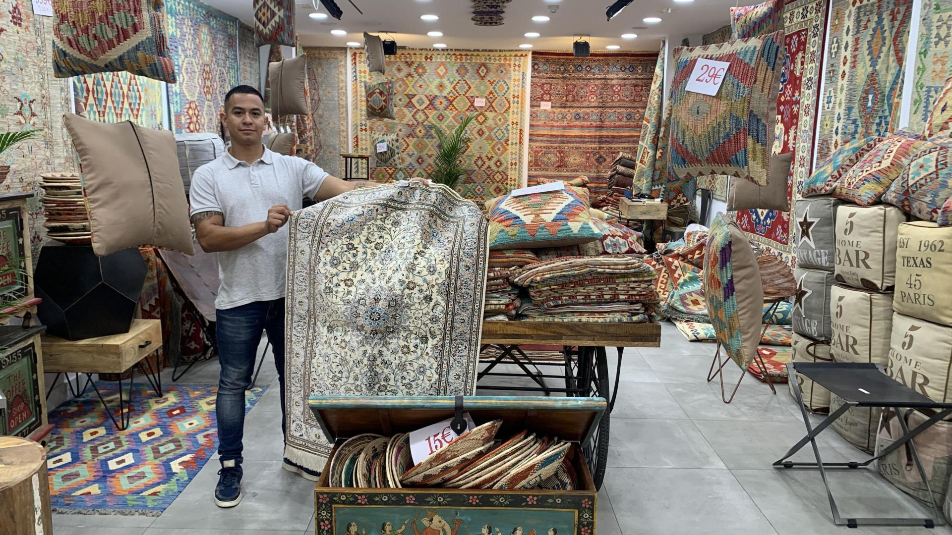 John, dependiente de House of Kilim, muestra una alfombra de seda