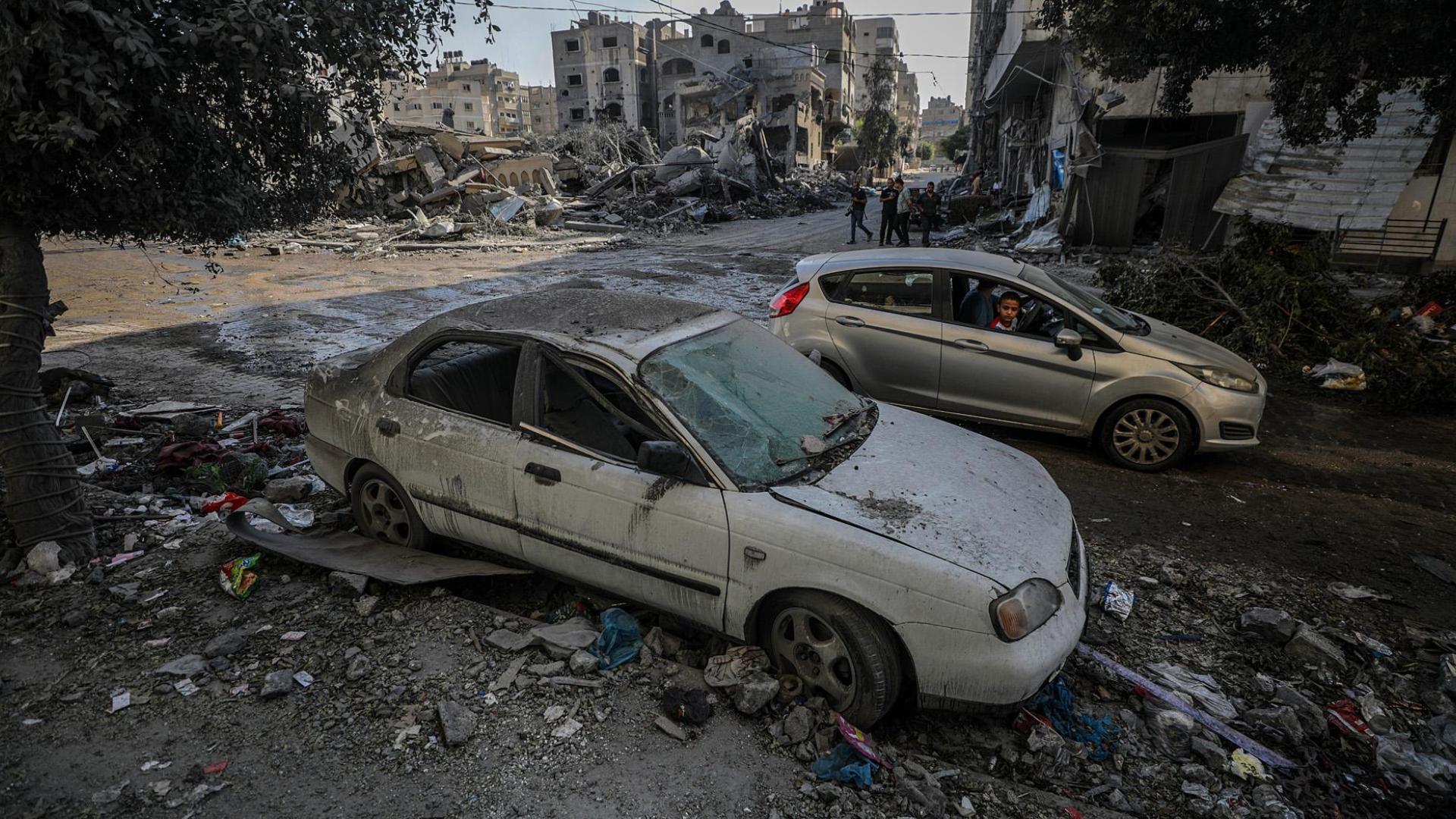 Un niño palestino mira un coche destruido por los bombardeos aéreos israelíes
