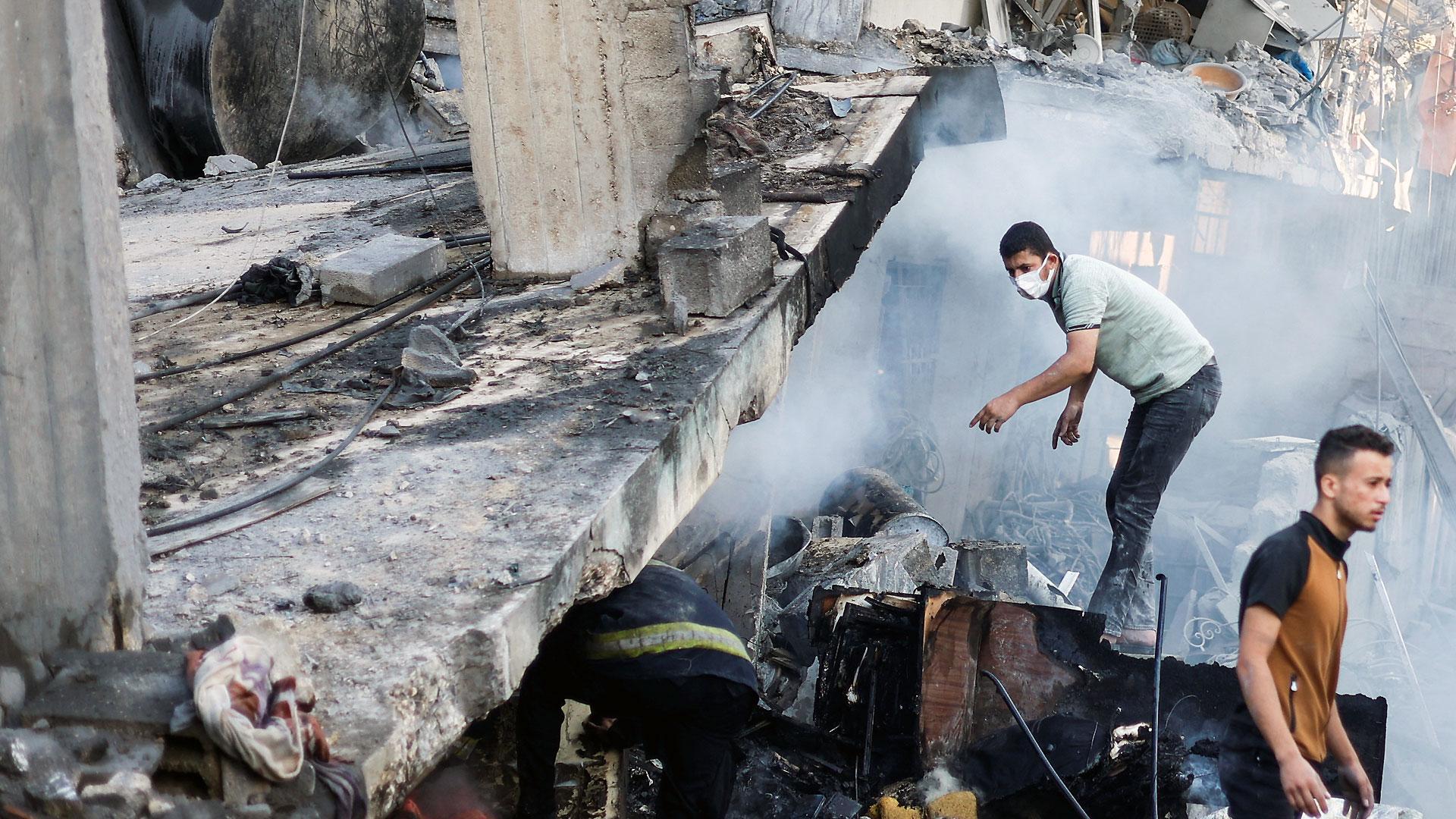 Varias personas buscan supervivientes en un edificio destruido en Khan Younis, al sur de Gaza