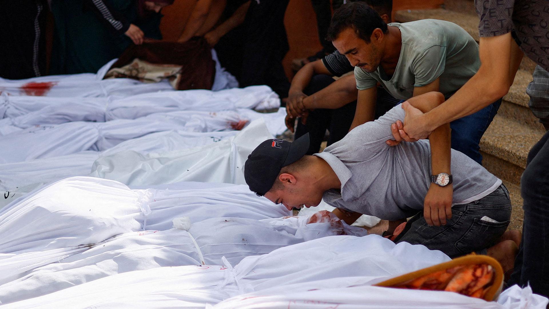 Un familiar de uno de los cientos de fallecidos en el ataque a un hospital de Gaza se despide con un beso en medio de otros cadáveres