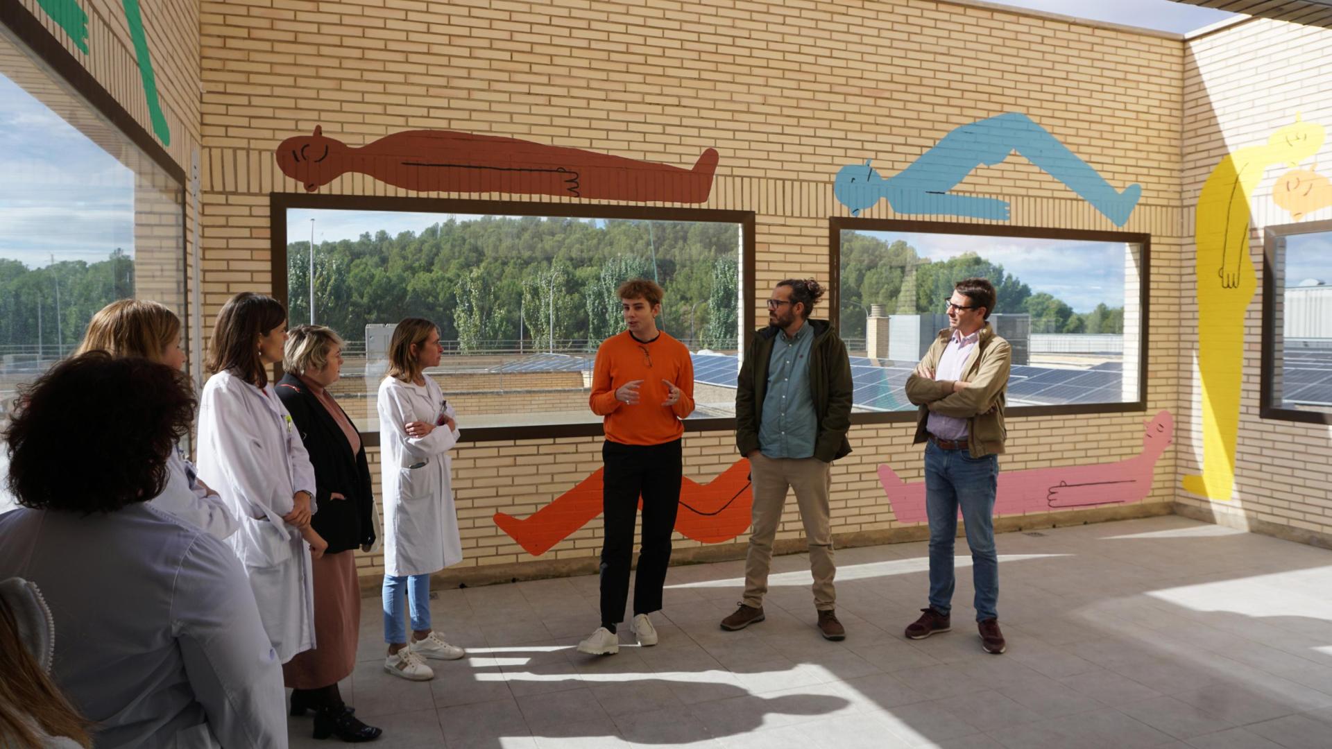 Diego Blasco, en el centro y ante varias figuras de su mural, explica su obra durante su presentación