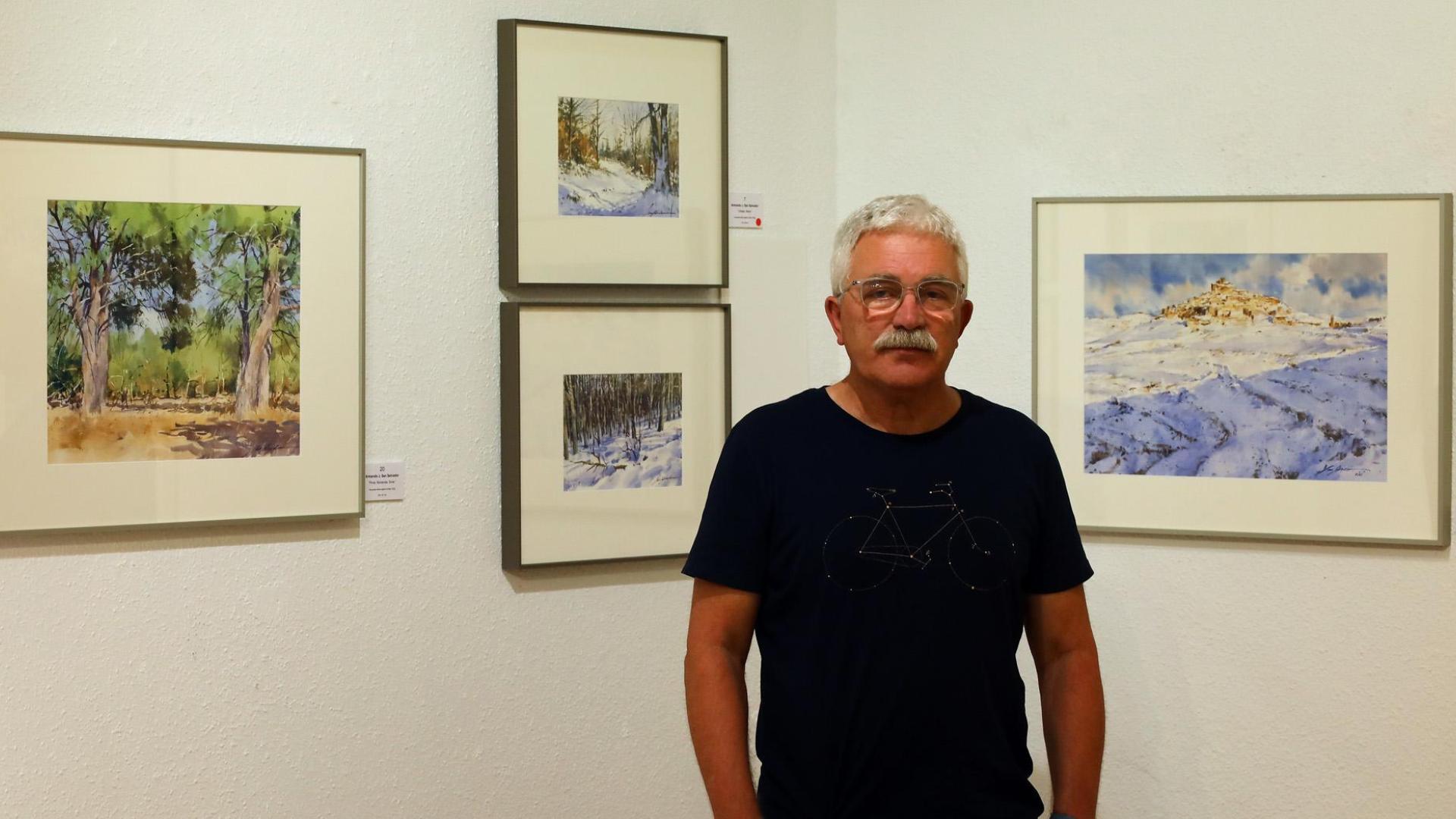 Armando San Salvador, junto a algunas de las acuarelas de la exposición Momentos, entre las que se encuentra la arbolea de pinos de Soria y Ujué nevado