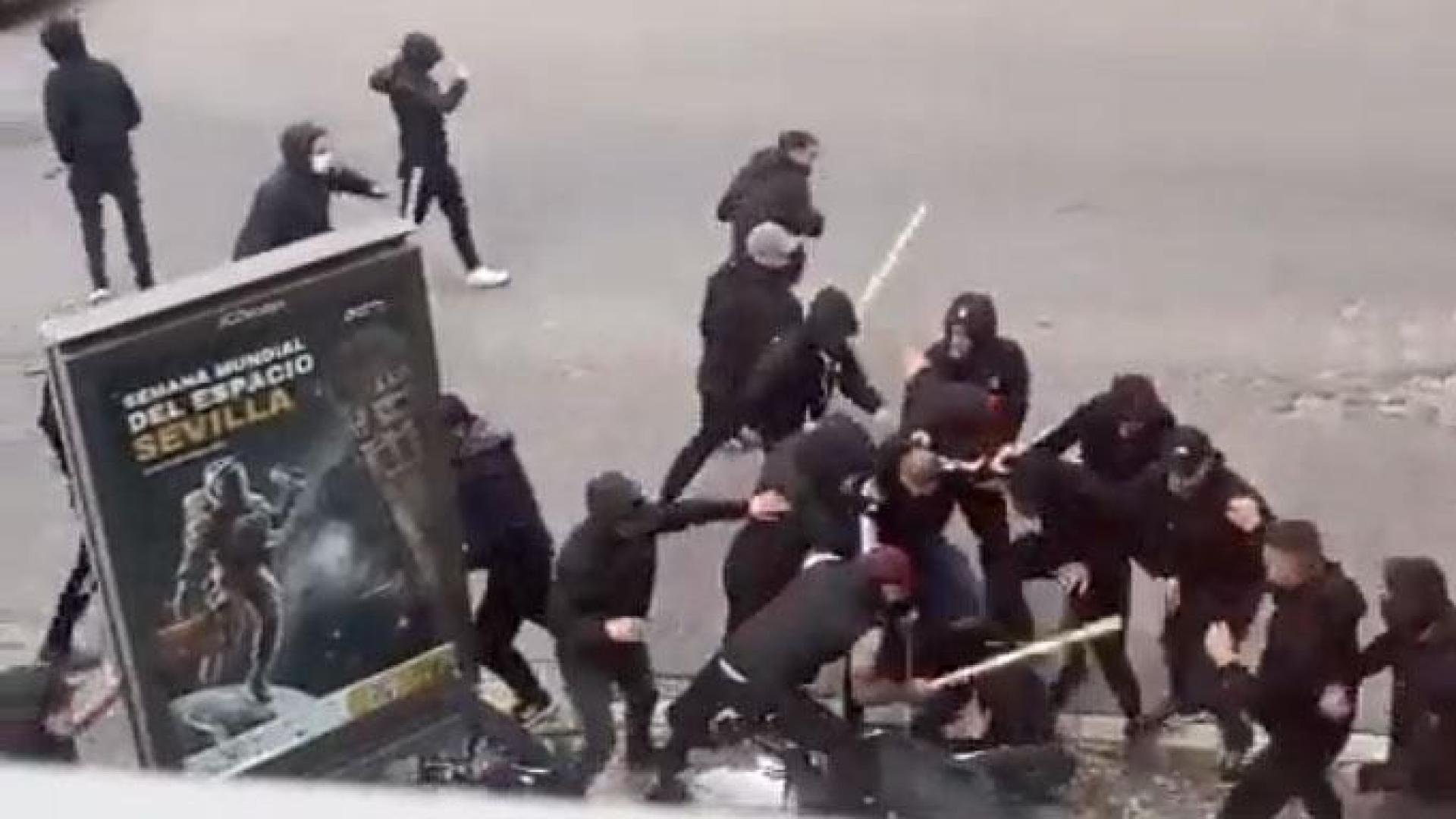 Un momento de la brutal paliza que varios ultras propinan con palos y barras a una persona que se queda inmóvil en el suelo junto a una moto este domingo en Sevilla