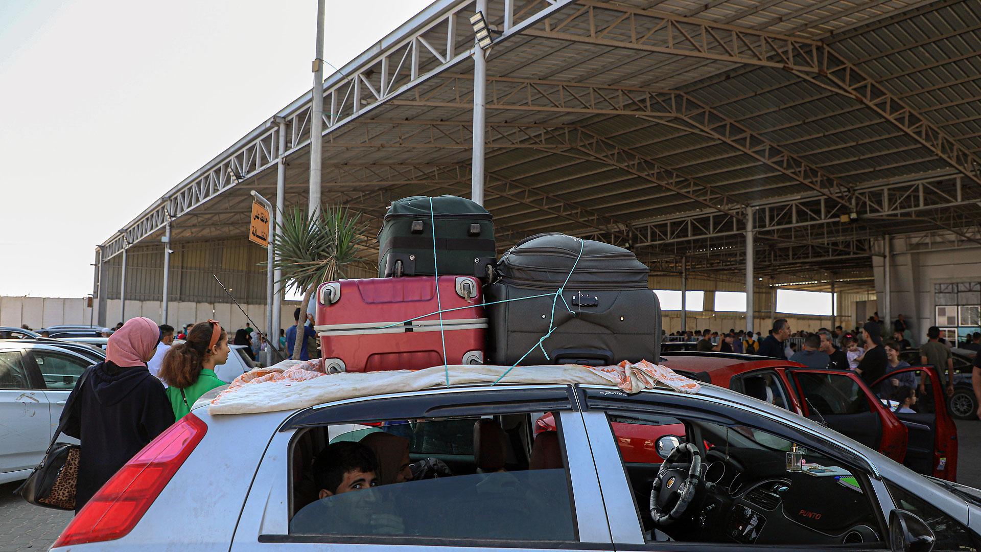 Un grupo de personas espera para abandonar la Franja de Gaza a través del paso de Rafá, en la frontera con Egipto
