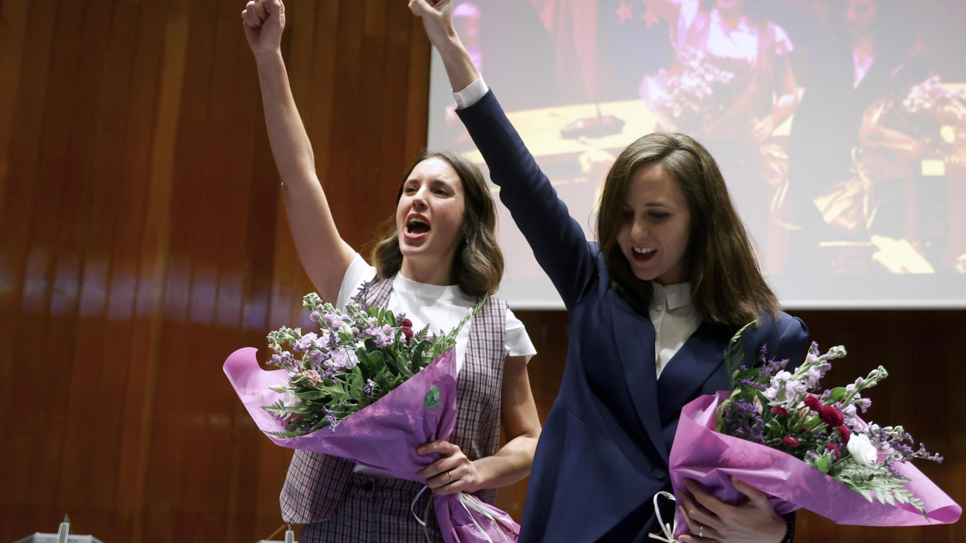 Las ya exministras Irene Montero y Ione Belarra levantan el puño en alto mientras son jaleadas por miembros de Podemos tras entregar sus respectivas carteras