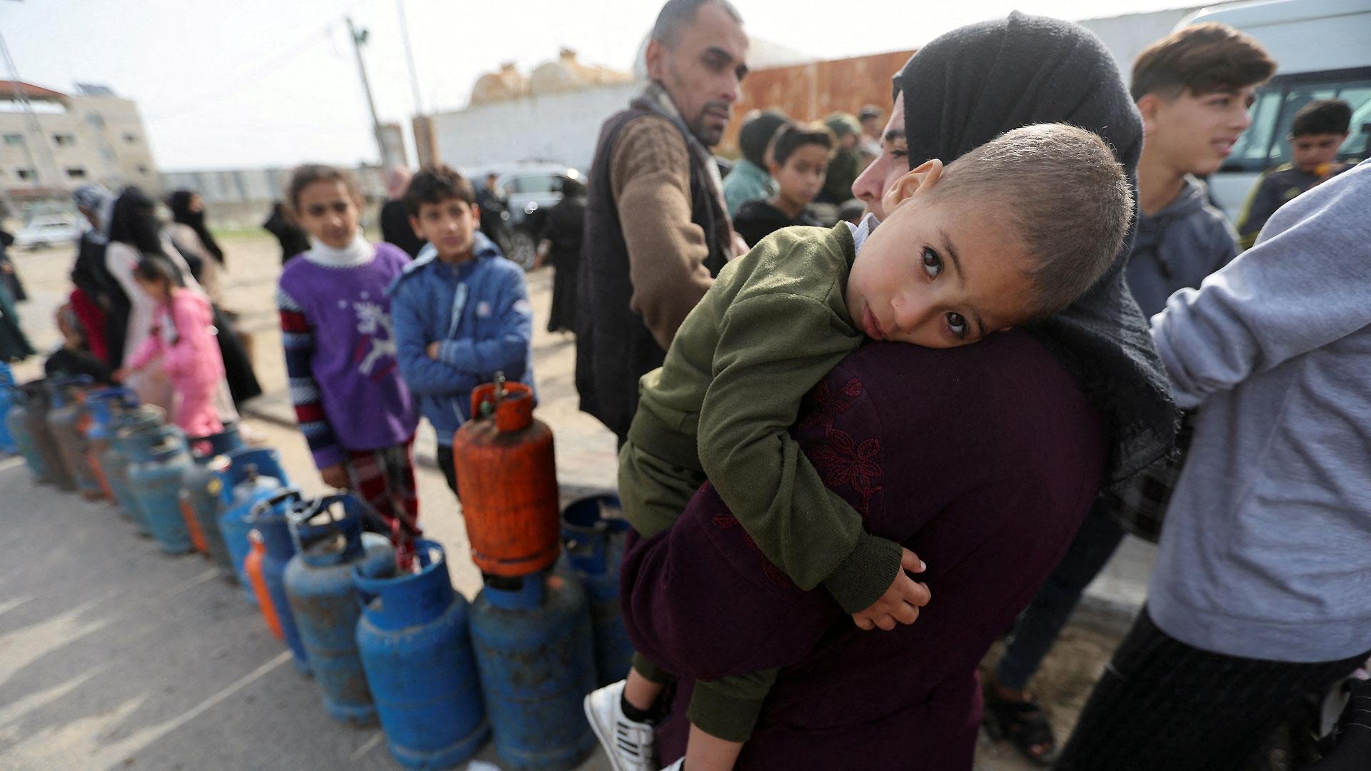 Una mujer porta en brazos a su hijo en un puesto de recogida de bombonas de gas al sur de la Franja de Gaza