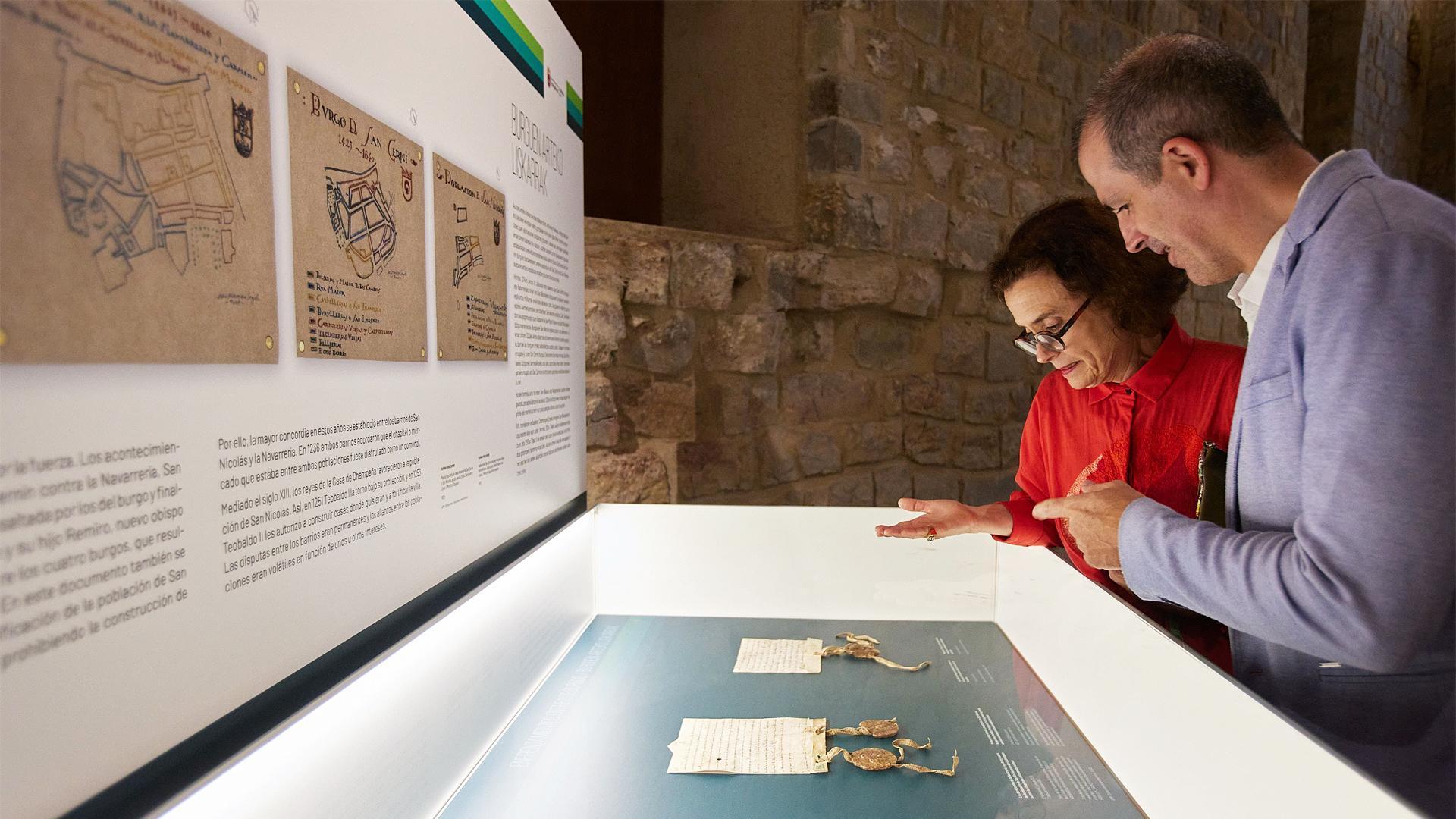 Dos personas atienden uno de los paneles informativos de la muestra./