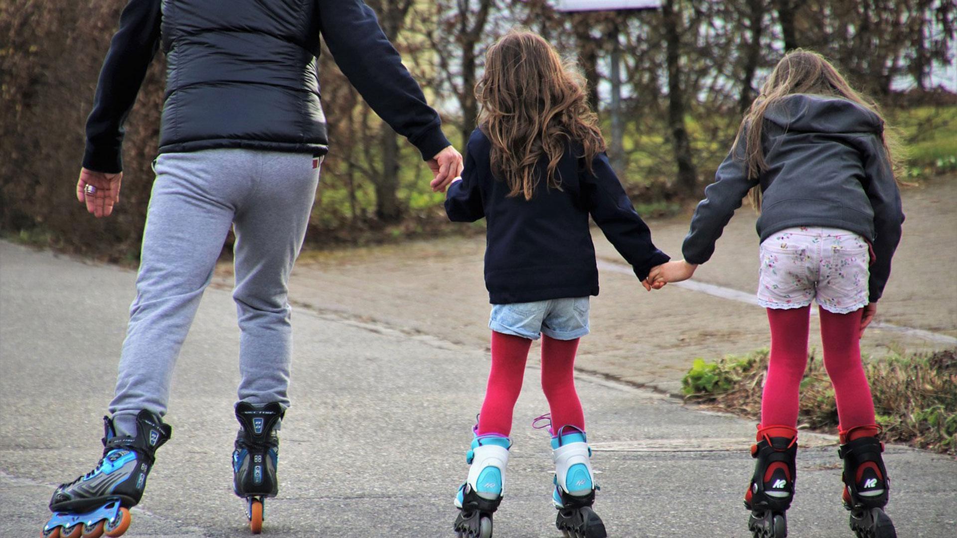 Dos niñas patinando con un adulto