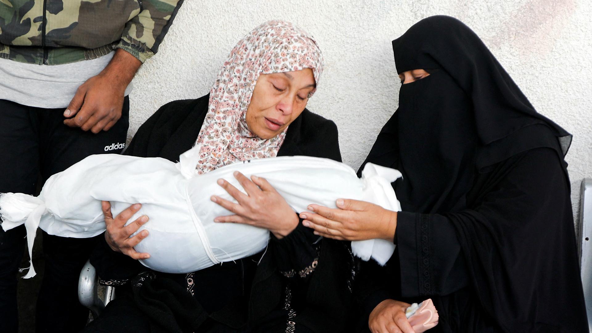 Dos mujeres palestinas, junto al cuerpo sin vida de un niño gazatí