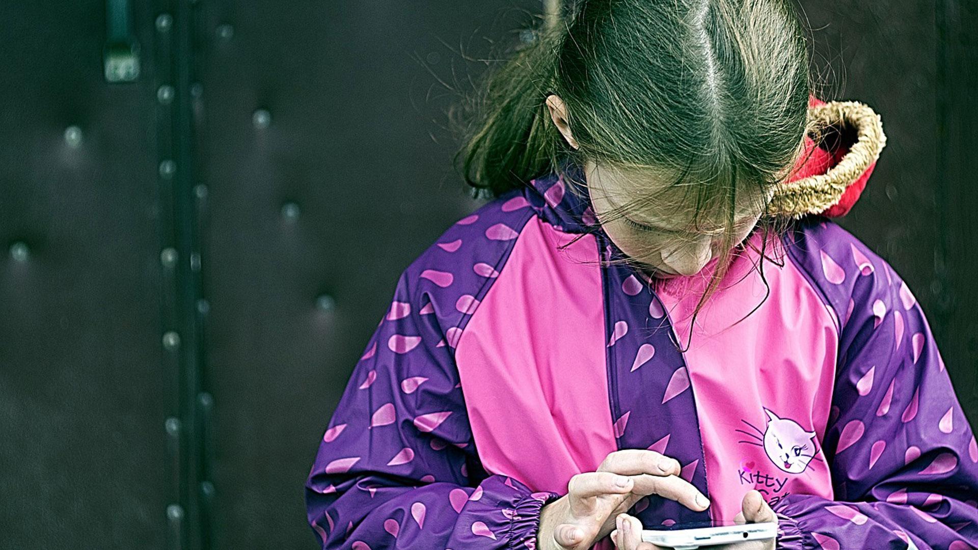 Una niña con un móvil en un recreo