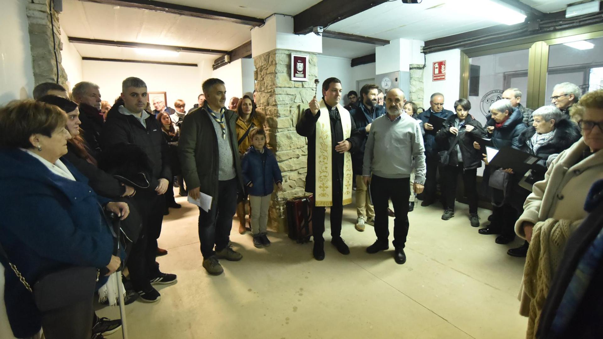 El párroco de Tafalla, Fermín Macías, bendice la exposición en presencia de los belenistas y quienes asistieron a la inauguración
