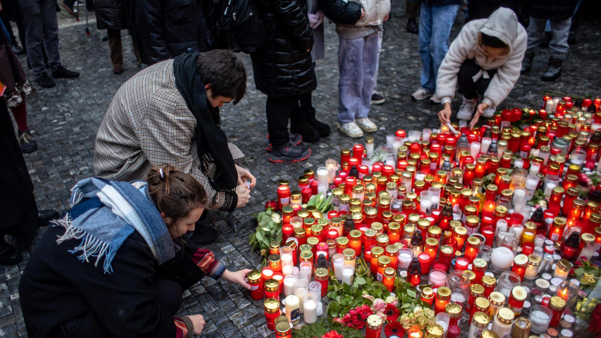 Varias personas encienden velas en la Universidad Carolina de Praga, donde tuvo lugar el tiroteo este 21 de diciembre