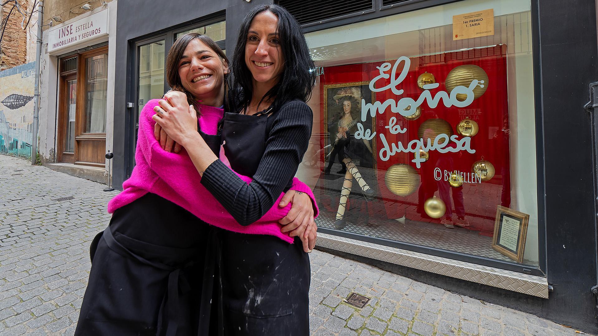 Soraya Echeverría López y Elena Sucunza Monterrubio junto a la peluquería del escaparate ganador./