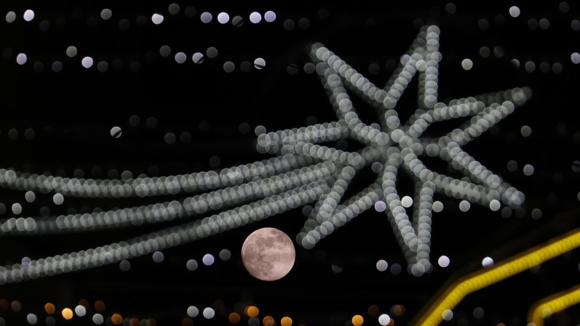 Fotografía de la última luna llena del año entre el alumbrado de navidad este lunes, día de Navidad, en Córdoba (Andalucia)