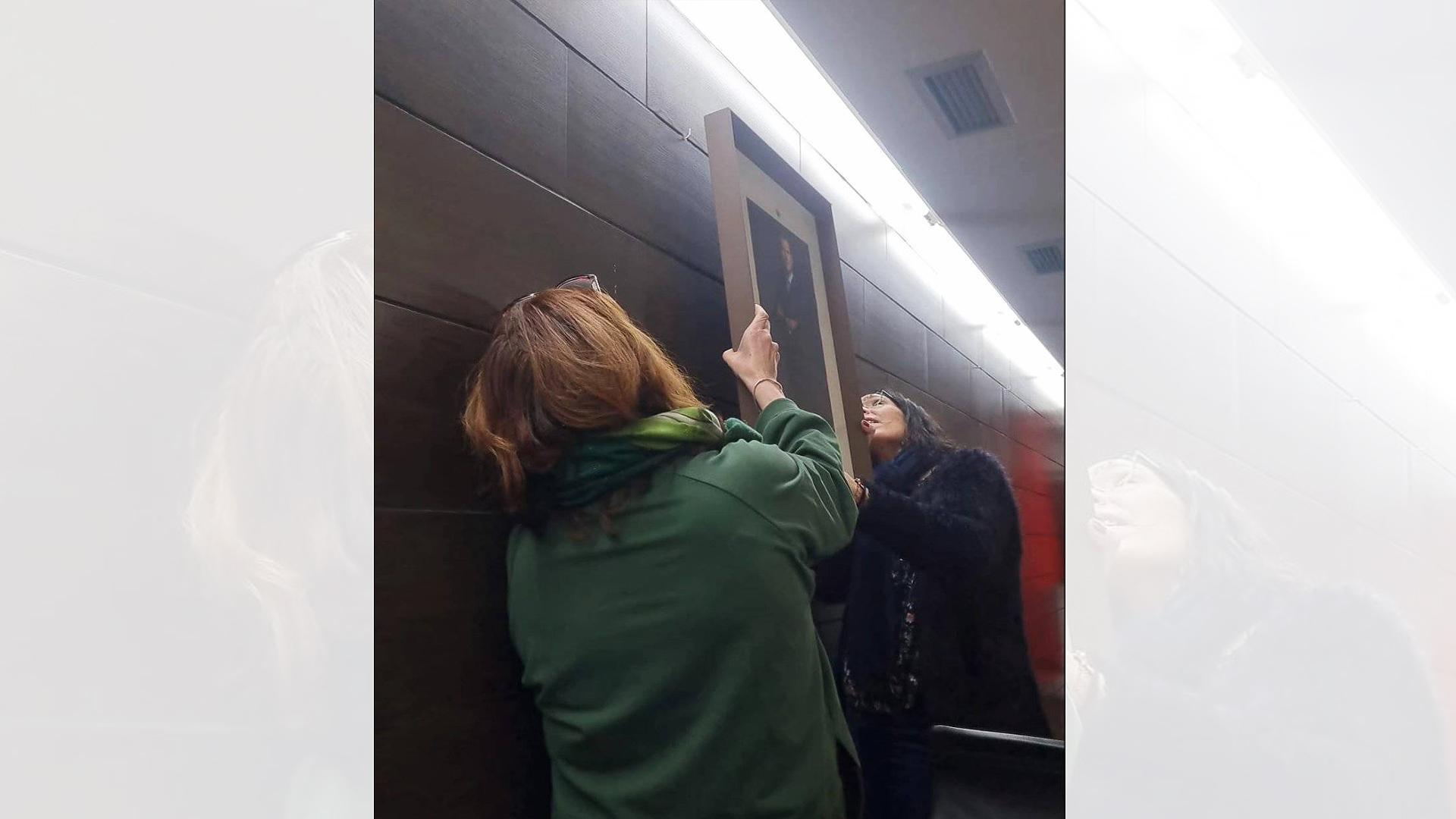 Ana Góngora (de espaldas) y la secretaria colocando el retrato real.