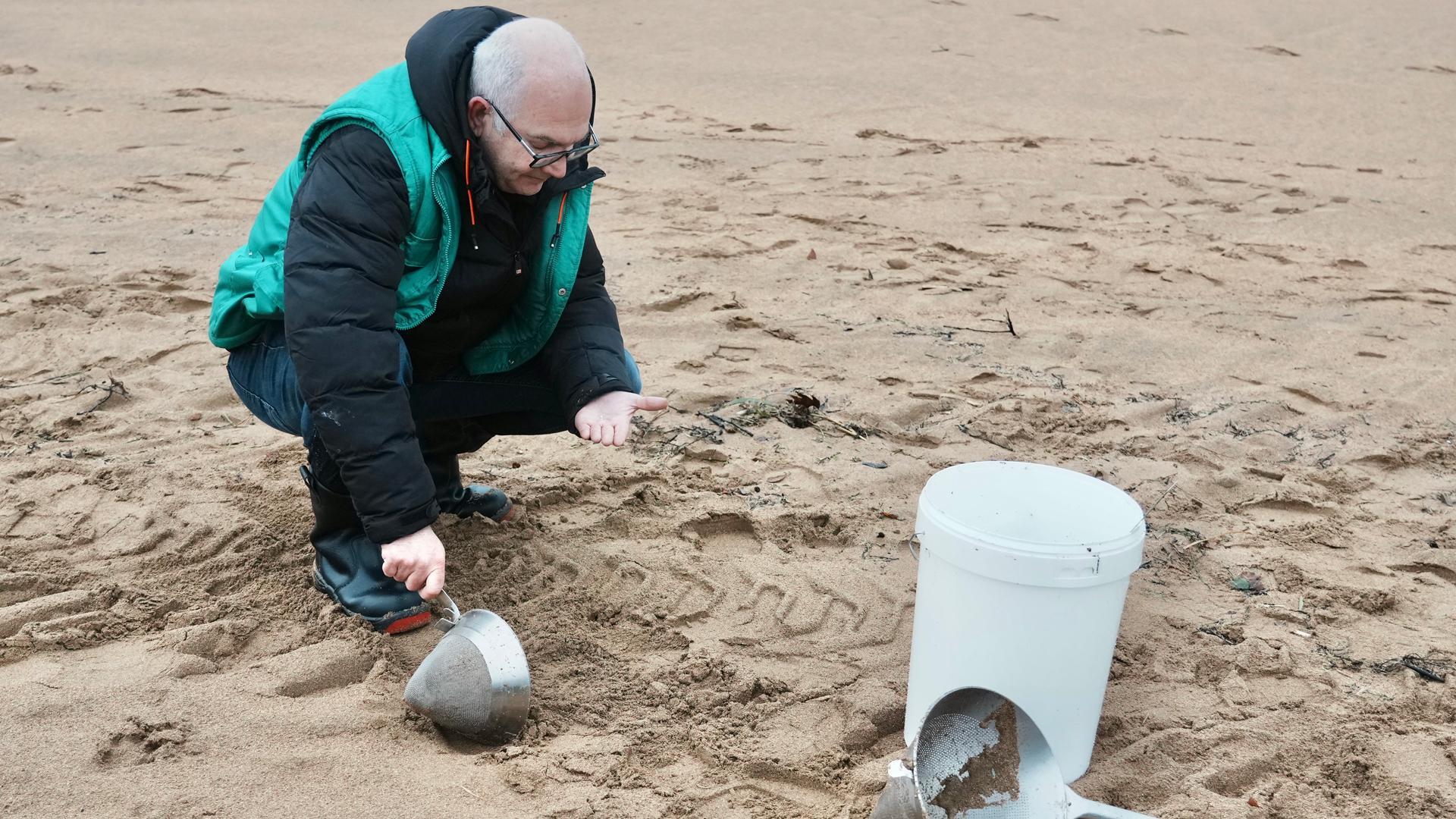 Un voluntario recoge pellets en la playa de La Arena, a 10 de enero de 2024, en Muskiz