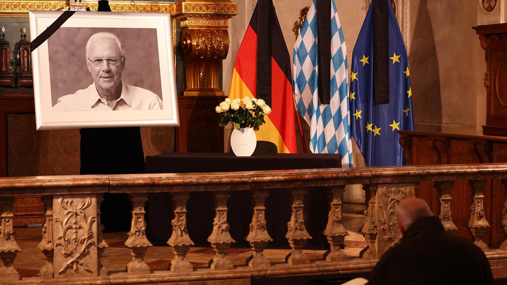 Un hombre firma en el libro de condolencias de Hofkapelle, en Munich, ante una foto de la leyenda del fútbol alemán Franz Beckenbauer.