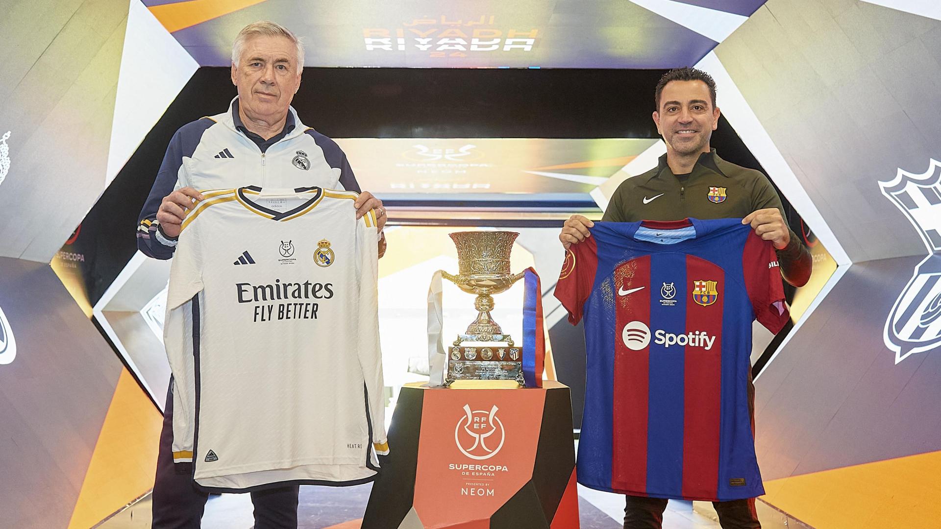 Carlo Ancelotti y Xavi Hernández, entrenadores del Real Madrid y Fútbol Club Barcelona respectivamente, posan con las camisetas de sus equipos en un acto previo a la gran final de este domingo.
