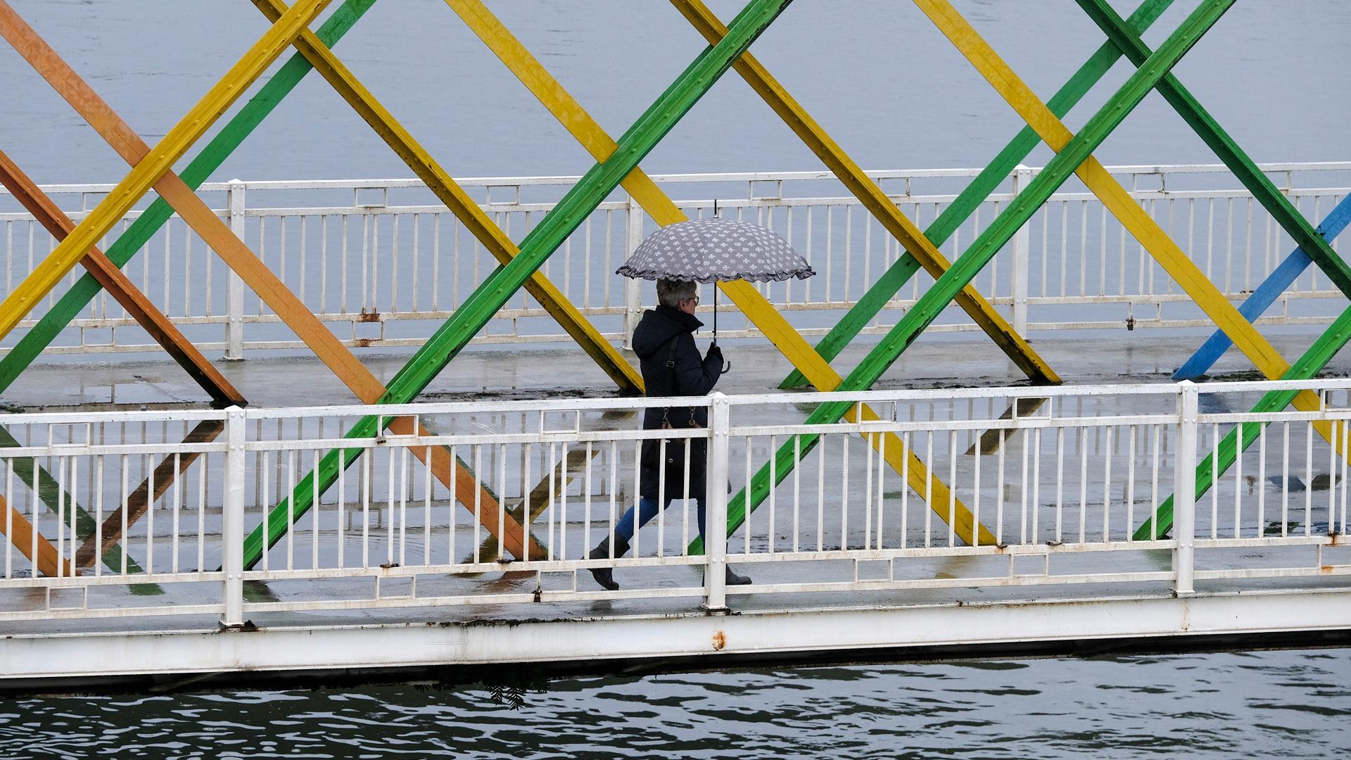 Una mujer con paraguas atraviesa el puente de San Sebastián en Avilés este martes lluvioso