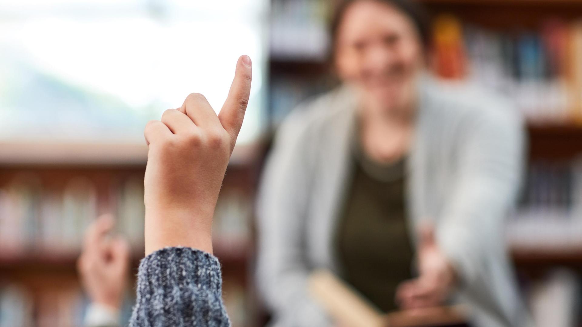 Un alumno levanta la mano para preguntar a la profesora.