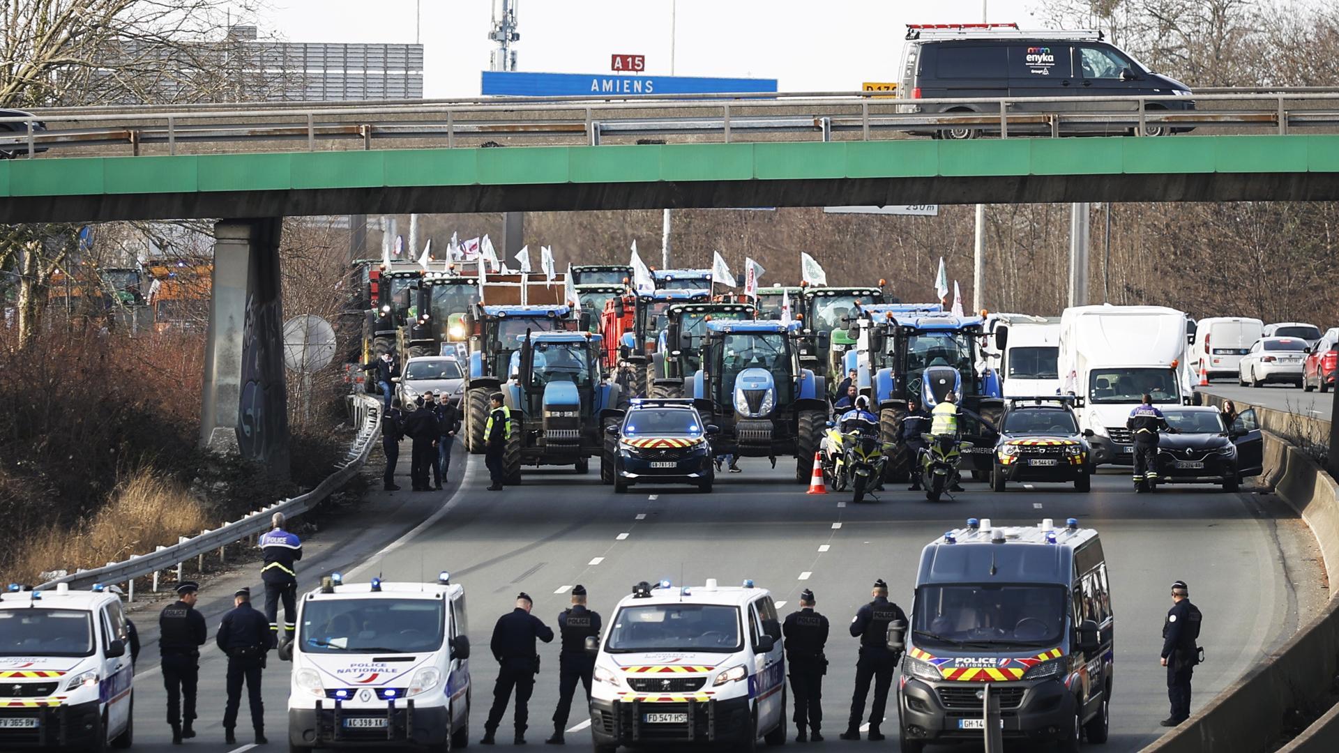 Agentes de policía vigilan decenas de tractores que participan en una manifestación en la autopista A15 cerca de Argenteuil, al norte de París