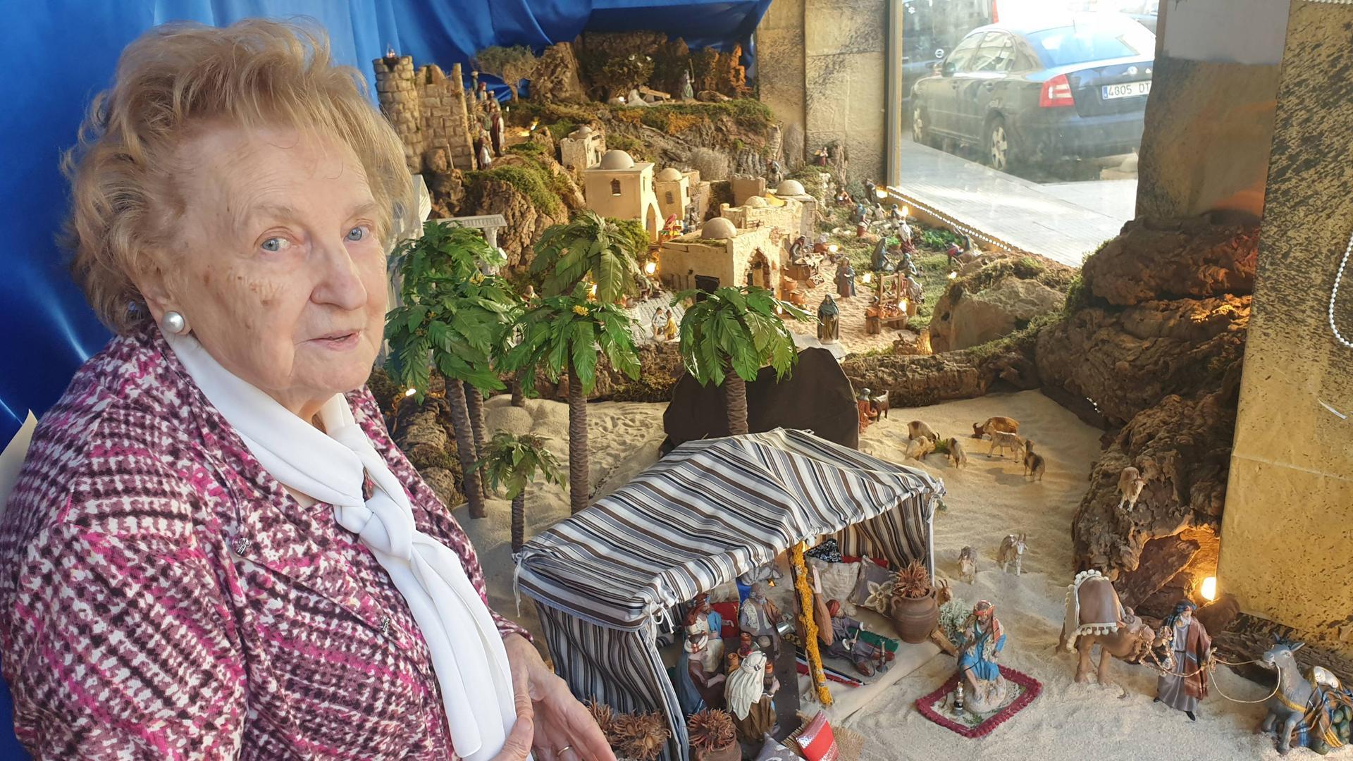 Elena Ciordia posa junto al belén que montan en el escaparte de su tienda en Burlada