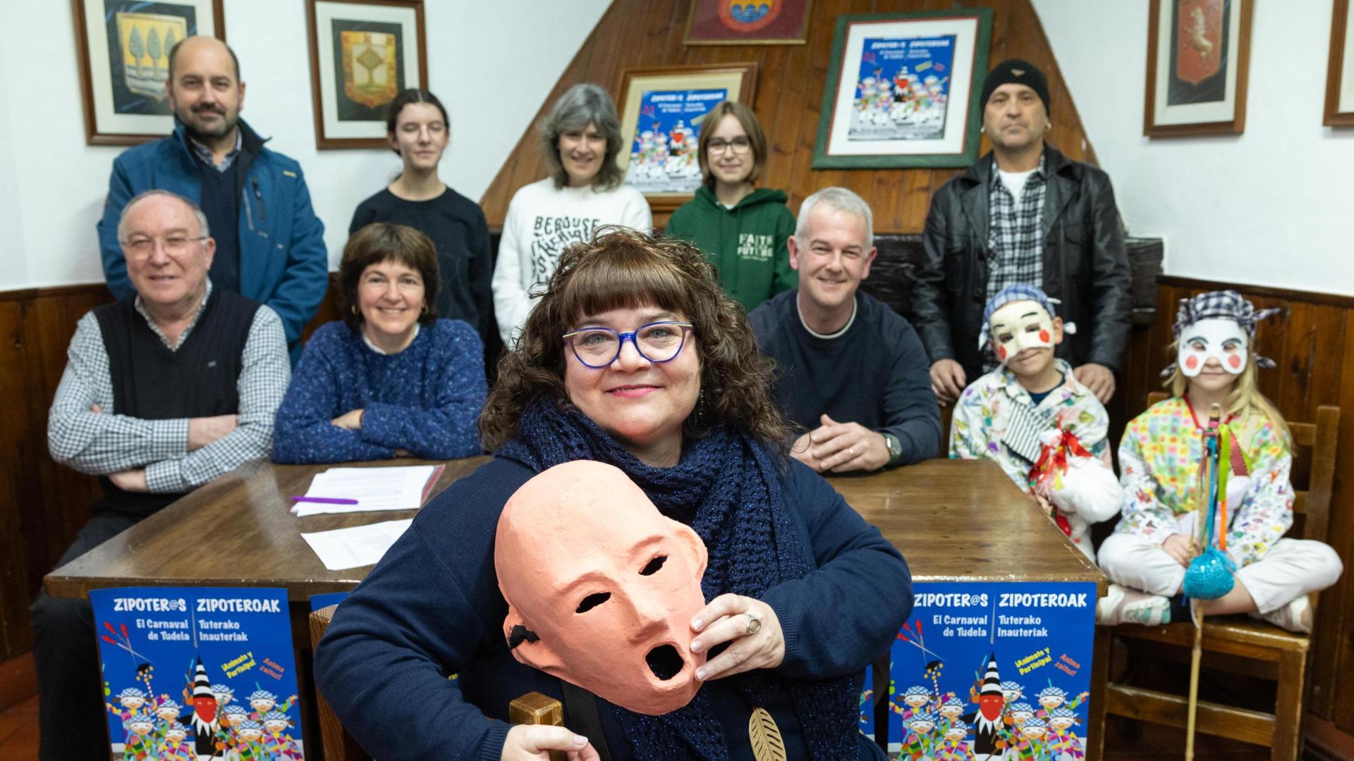 La Zipotera Mayor del Carnaval de Tudela 2024, Ane Domínguez Marco, posa con una máscara en la sede de la peña Beterri ante parte de los miembros de la Asociación de Amigos de los Zipoteros de la capital ribera