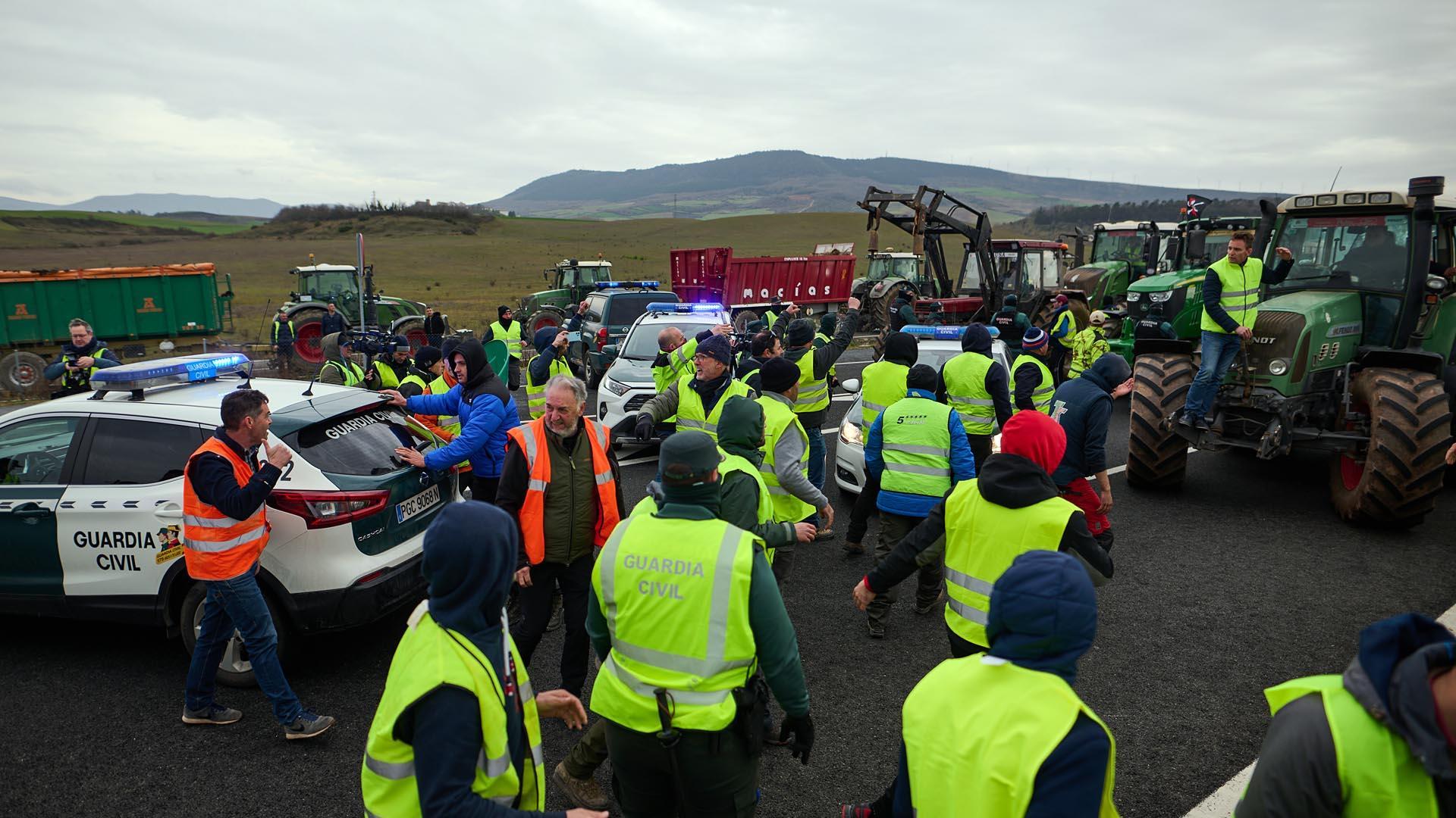 Fotos del momento en el que los agricultores apartan a la fuerza dos coches de la Guardia Civil en la A-12 para seguir hacia Pamplona.