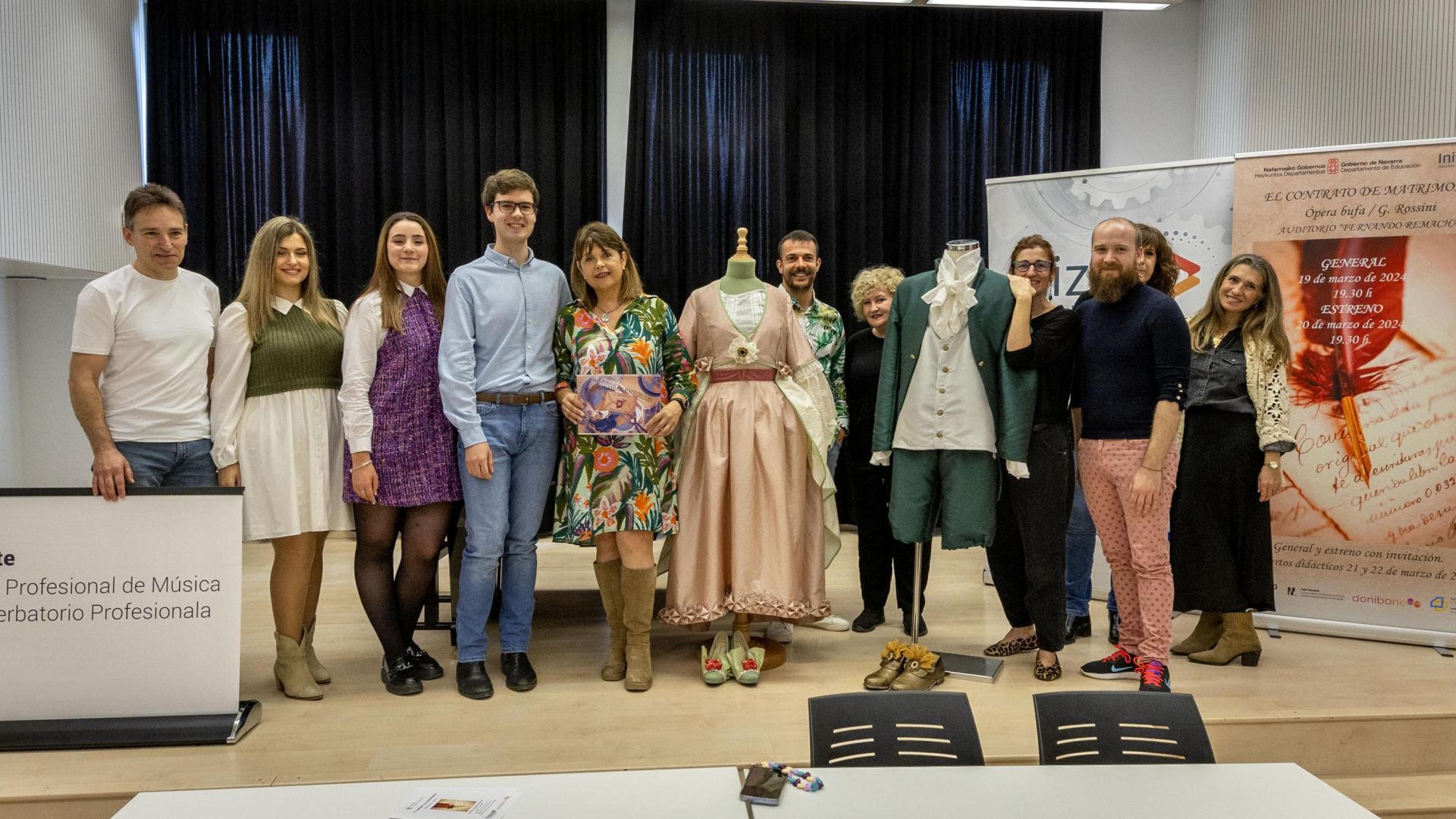 rofesores y alumnos que han trabajado en la ópera El contrato de matrimonio, posando junto a dos trajes creados por los alumnos del Ciclo de Textil y Confección del centro FP Donibane.