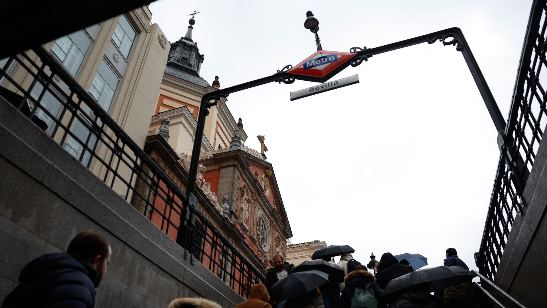 La gente sale con paraguas de la estación de Metro de Sevilla en el centro de Madrid este sábado
